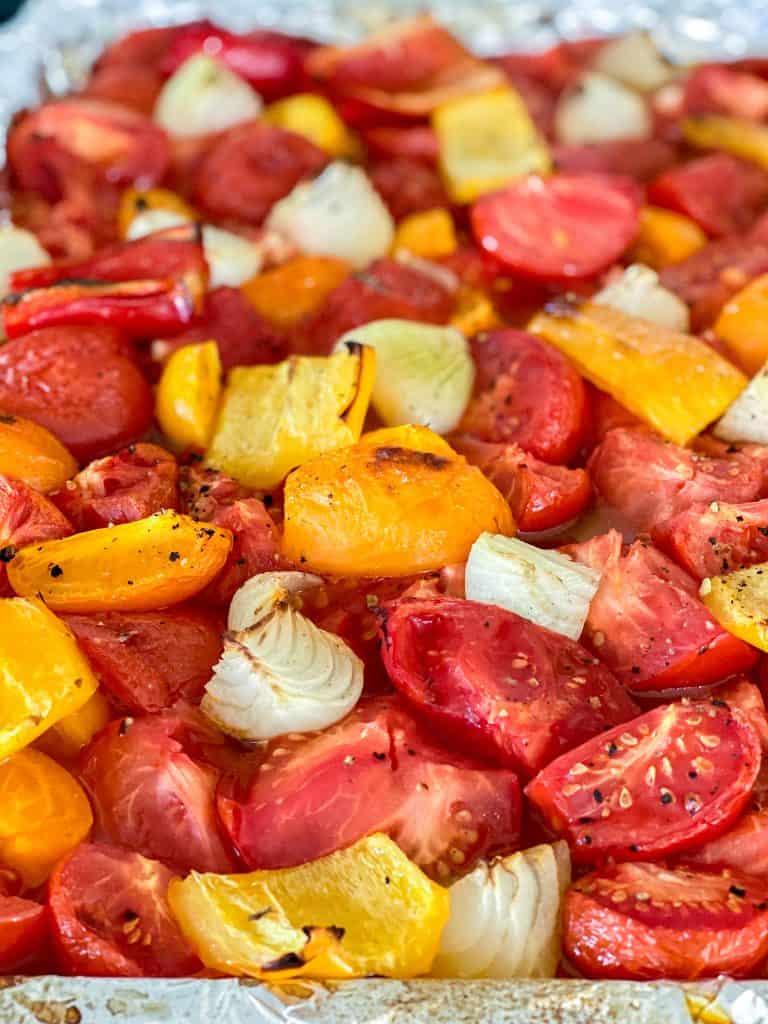 Roasted tomatoes and onions on a baking sheet. 