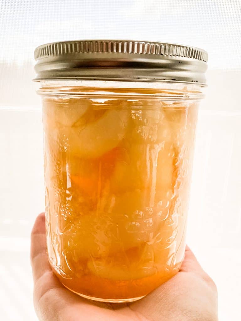 Hand holding jar of chai spiced pears.