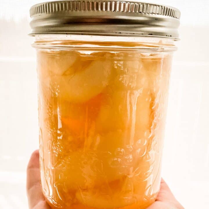 Hand holding jar of chai spiced pears.