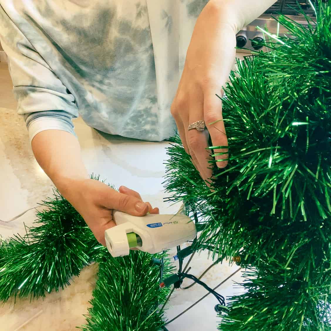 Finishing up gluing the green garland to the Christmas tree.