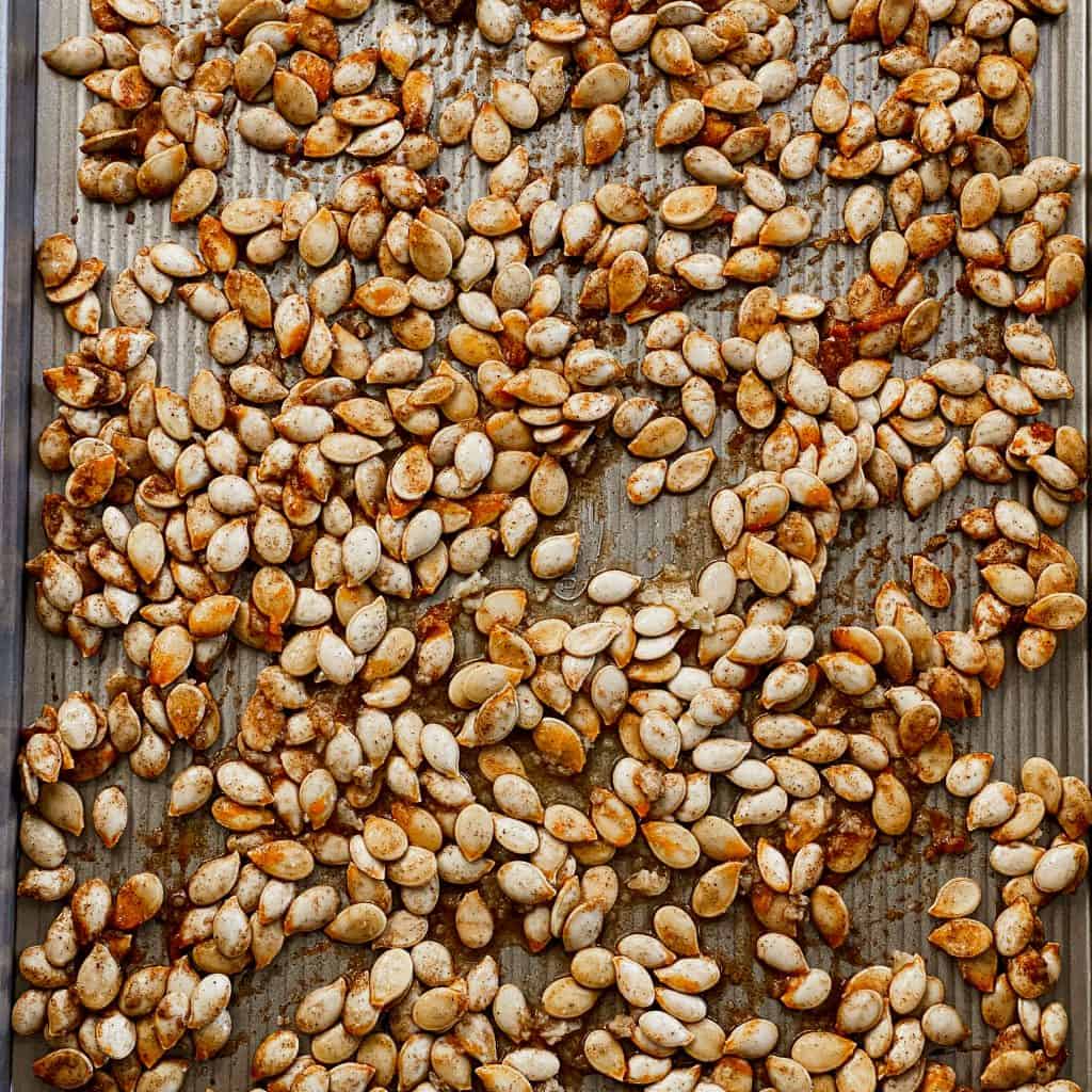 Sweet and Salty Chai spiced pumpkin seeds spread out on a cookie sheet.