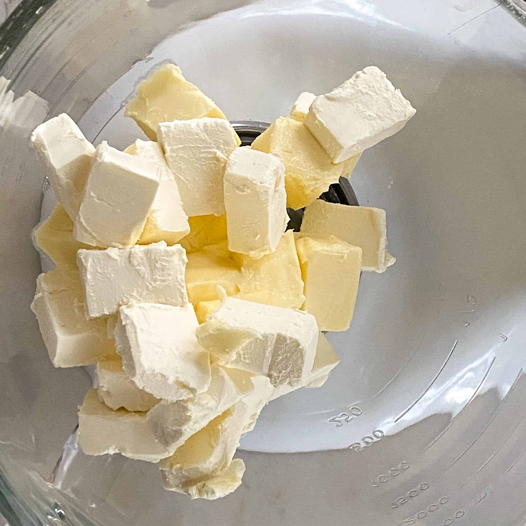 Cubed cream cheese and butter in a glass mixing bowl.