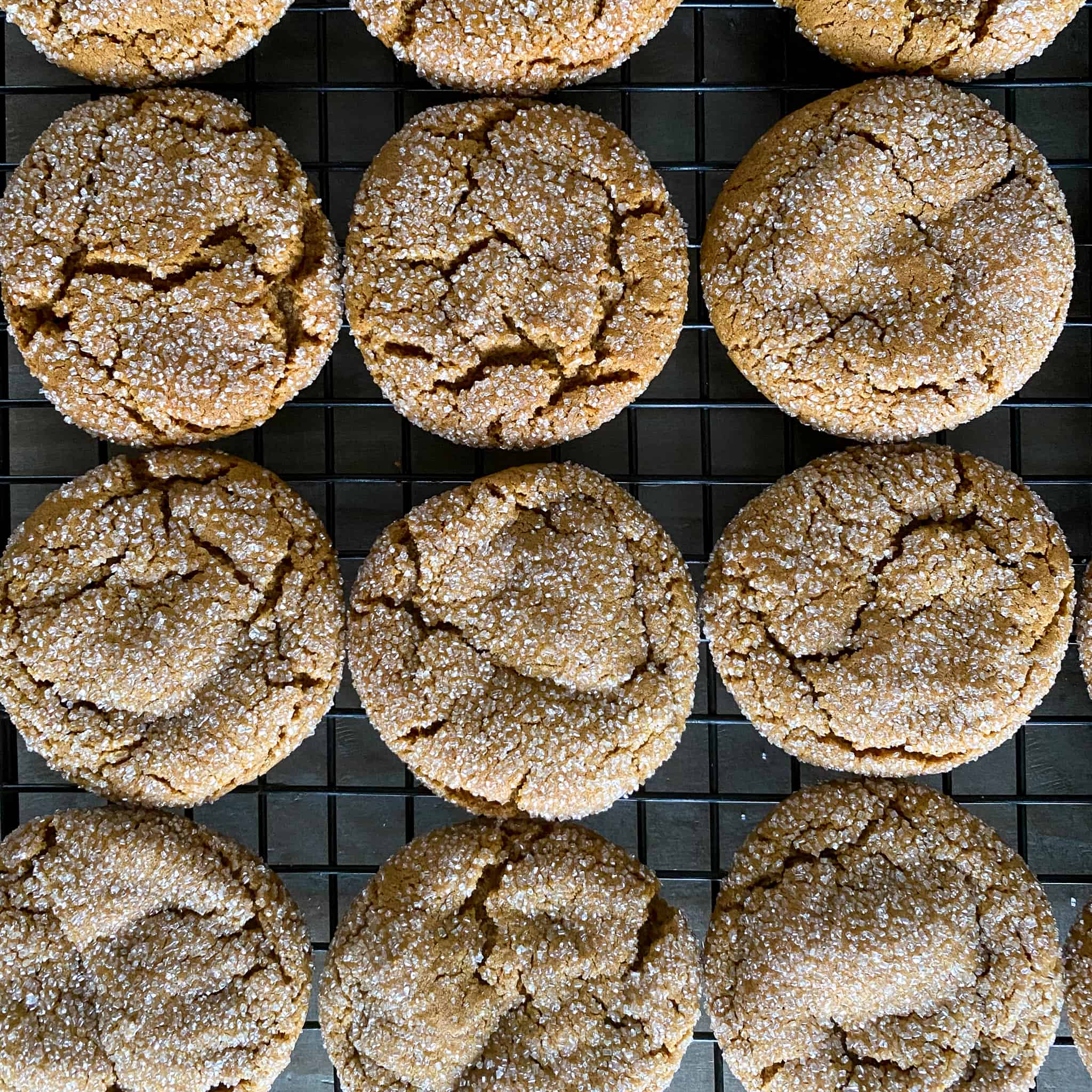 Old fashioned ginger snap cookies on a black cooling rack.