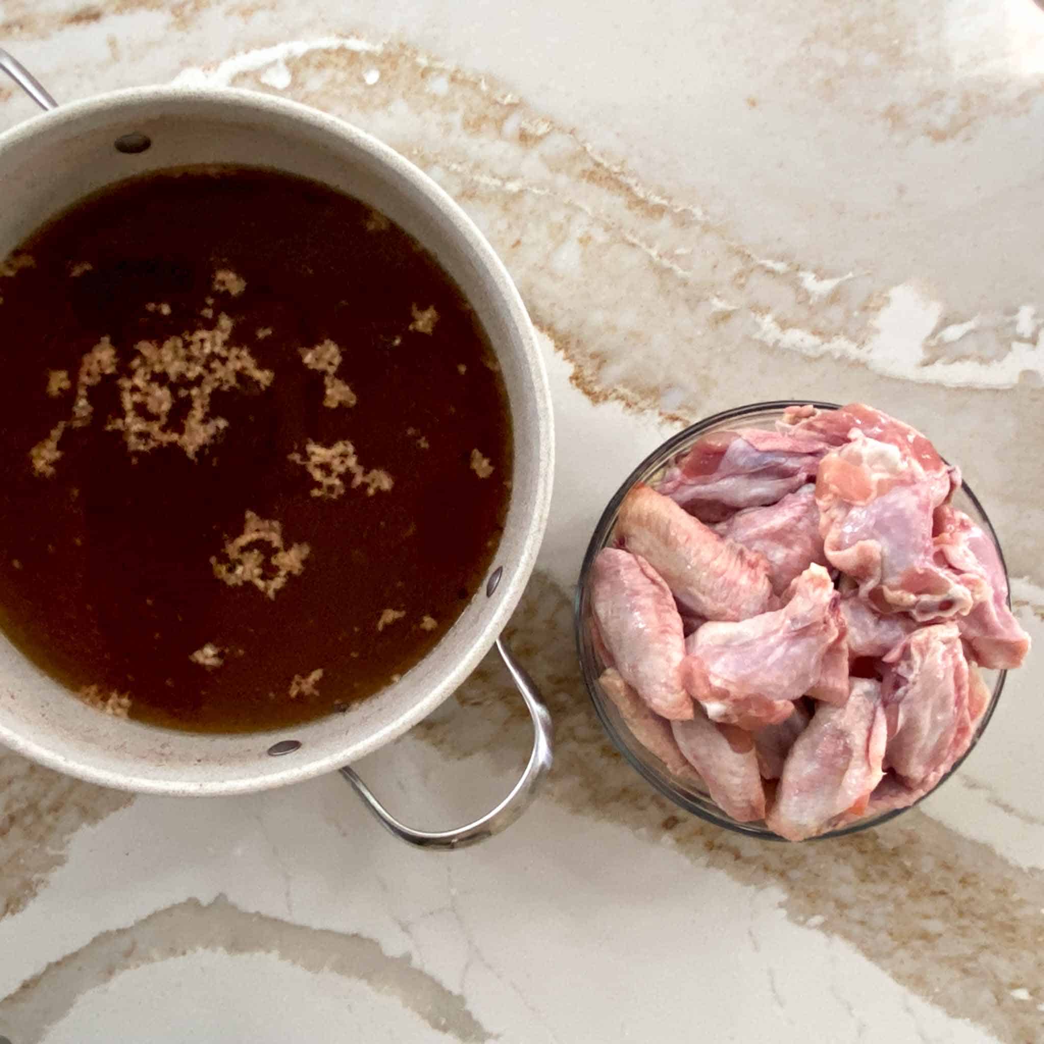 Simple chicken brine in a stock pot with raw wings beside.