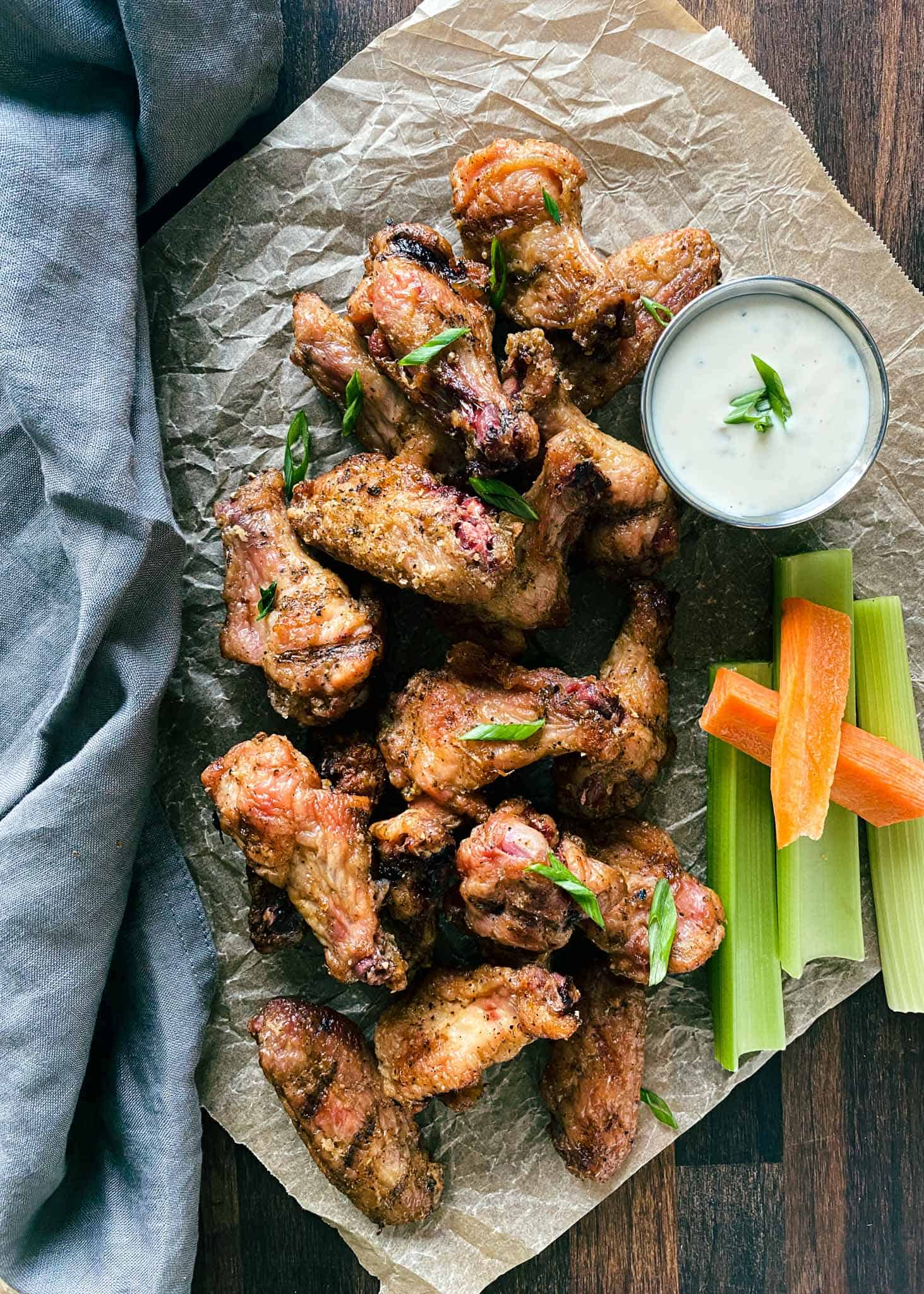 Smoked crispy chicken wings with dipping sauce and fresh vegetables.