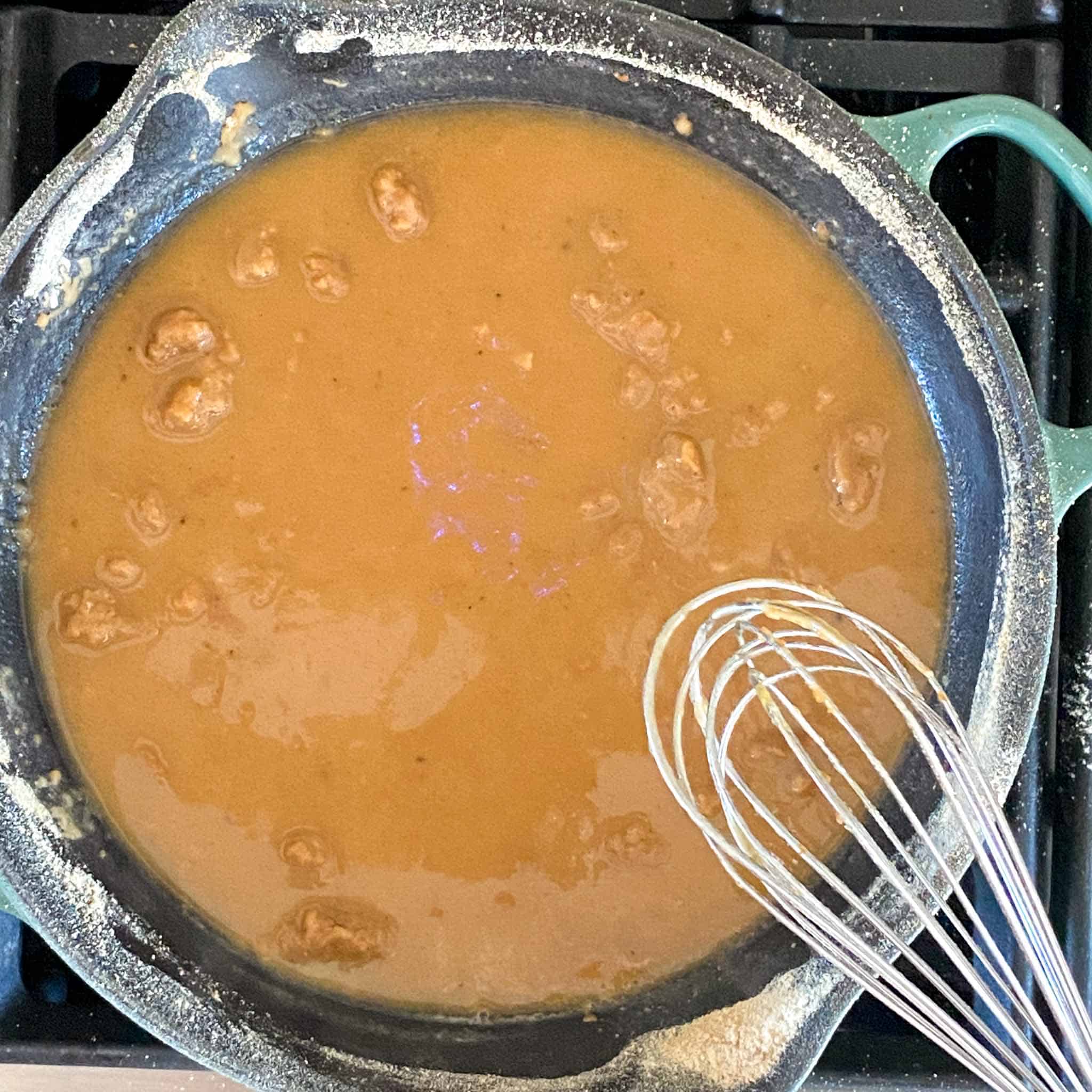 Roux forming in a cast iron pan being whisked.