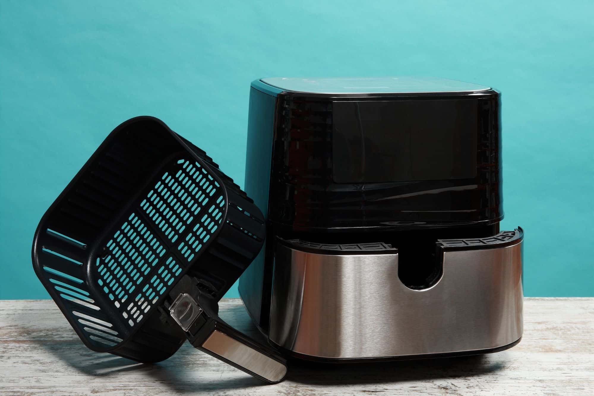 Air fryer with the basket out and a blue background.
