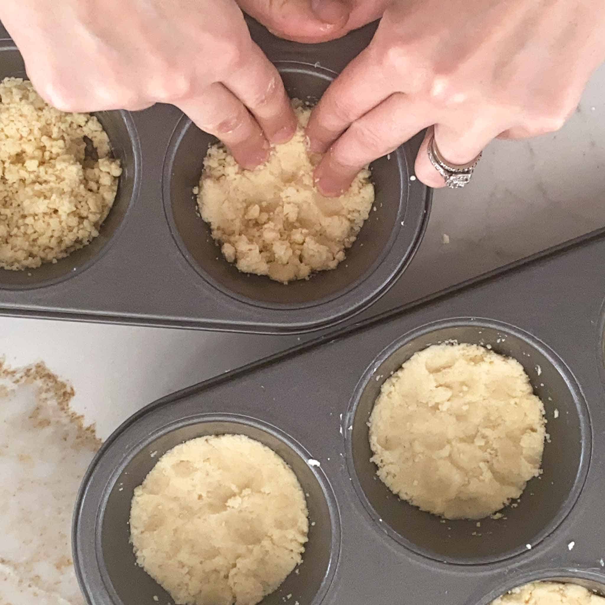 Crumble being packed into jumbo muffin tins.