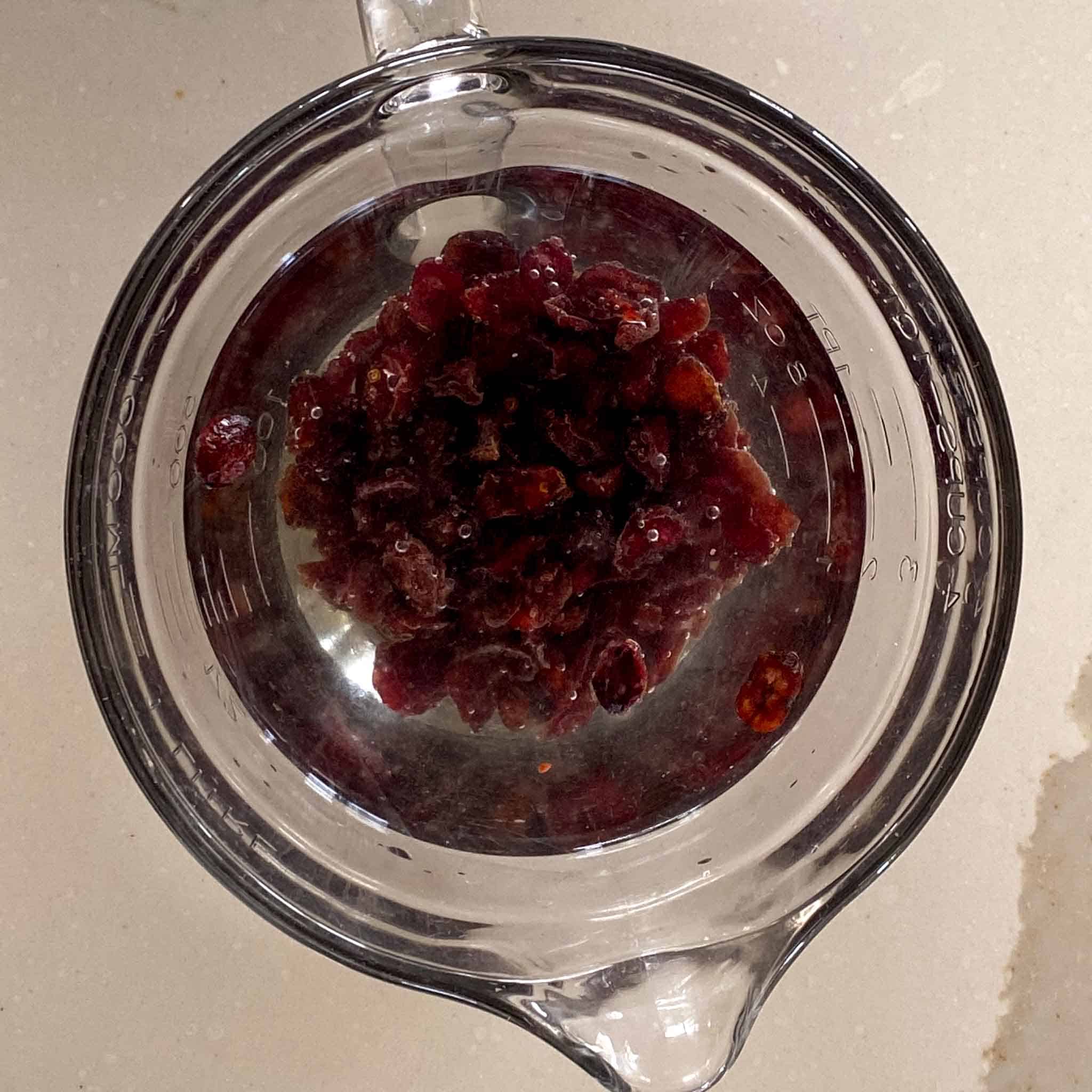 Cranberries rehydrating in a large cup of warm water.