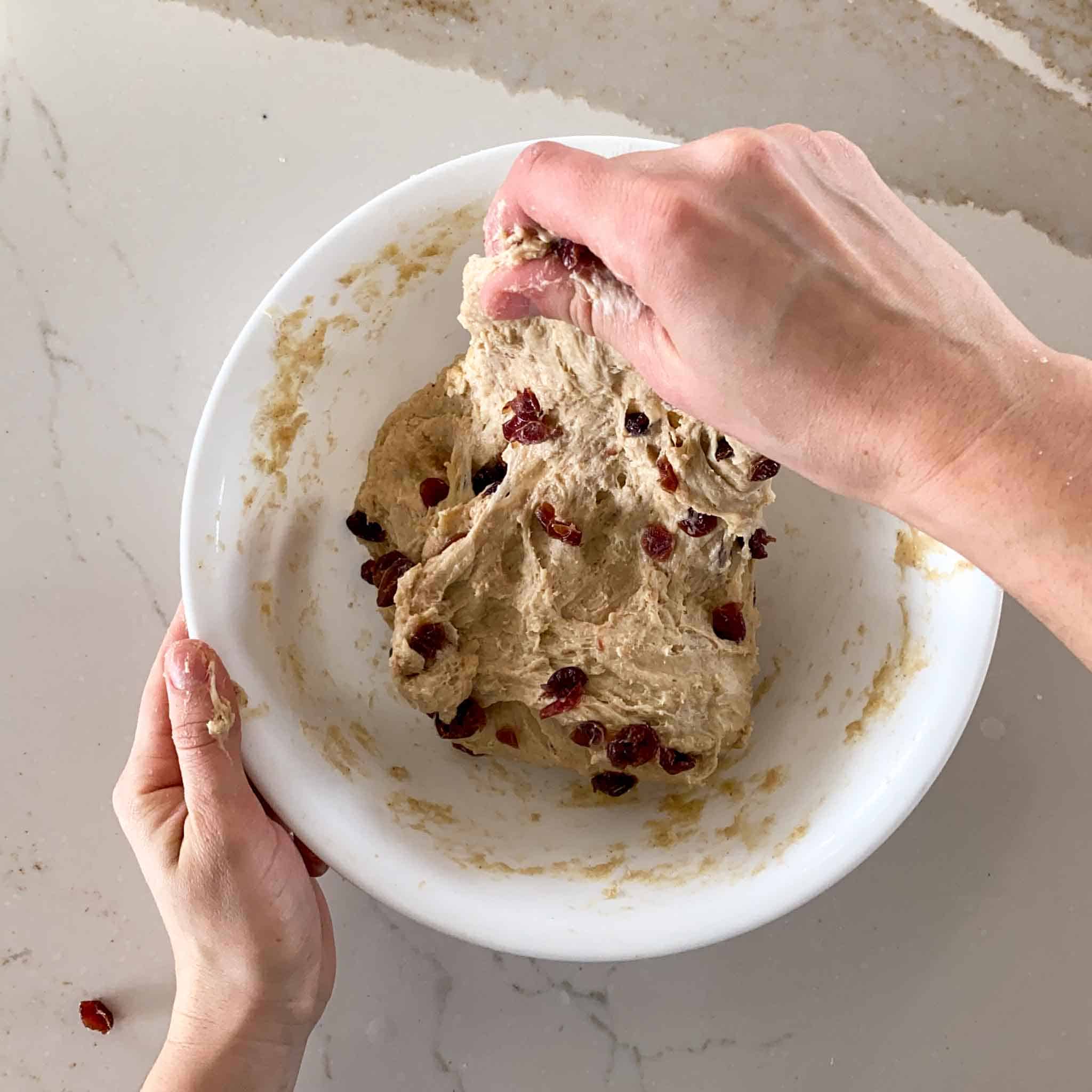 Stretching cranberry sourdough as part of the stretch and fold process for sourdough hot cross buns.