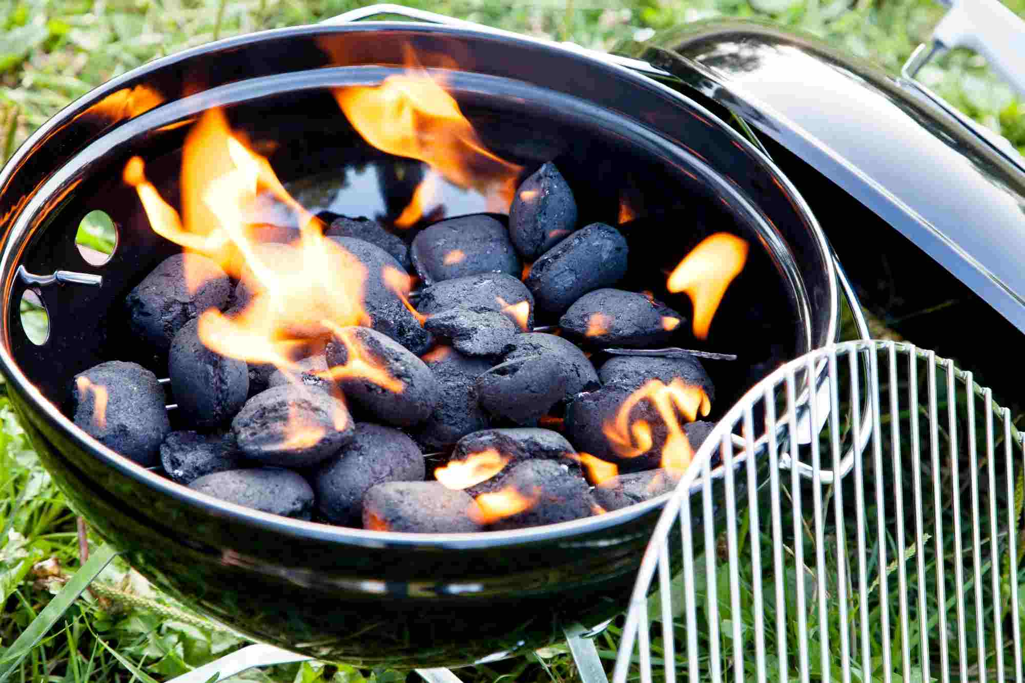 A black charcoal grill filled with coals and flames.