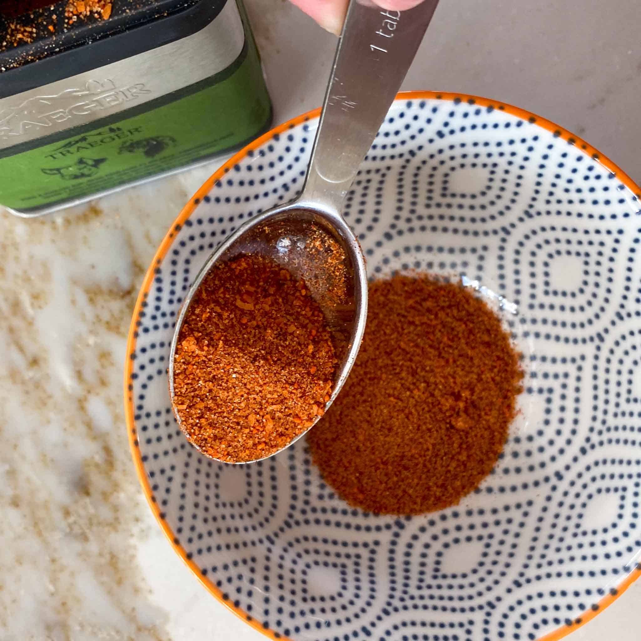 Traeger Pork + Poultry Rub being spooned into a bowl.