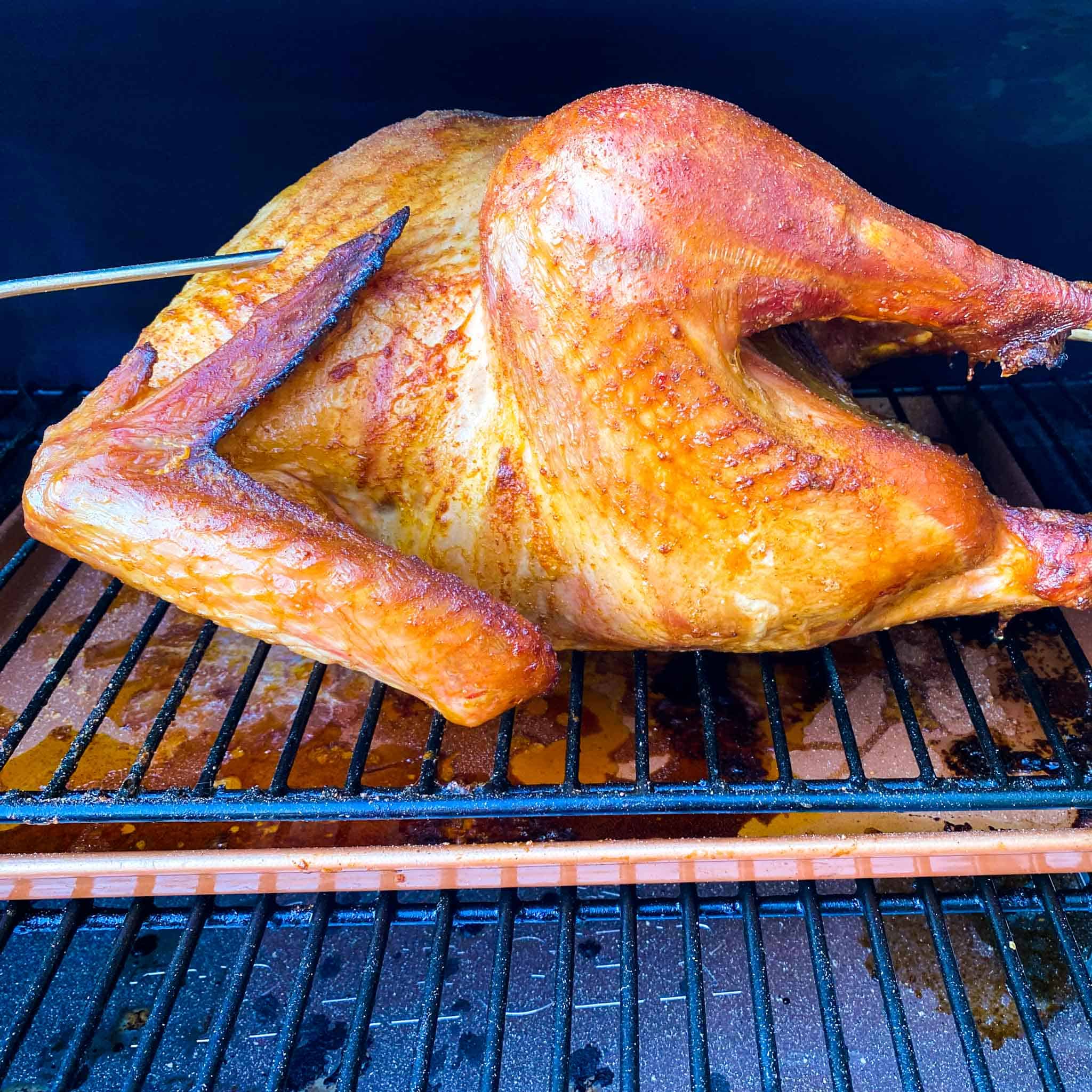 Smoked Turkey sitting on a traeger pellet grill with a meat probe inserted.
