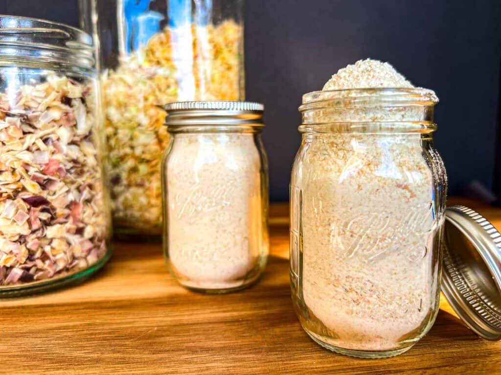 Garlic powder in a mini mason jar with two large jars of dehydrated onions in the background.