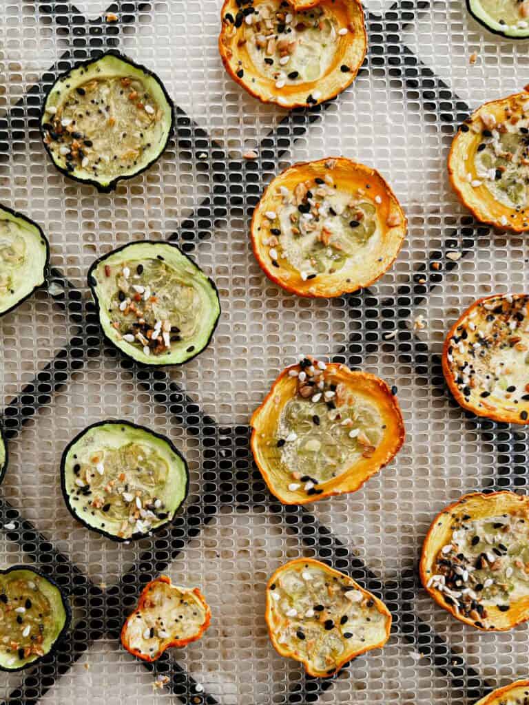 Zucchini rounds on a dehydrator tray to make everything bagel zucchini chips.