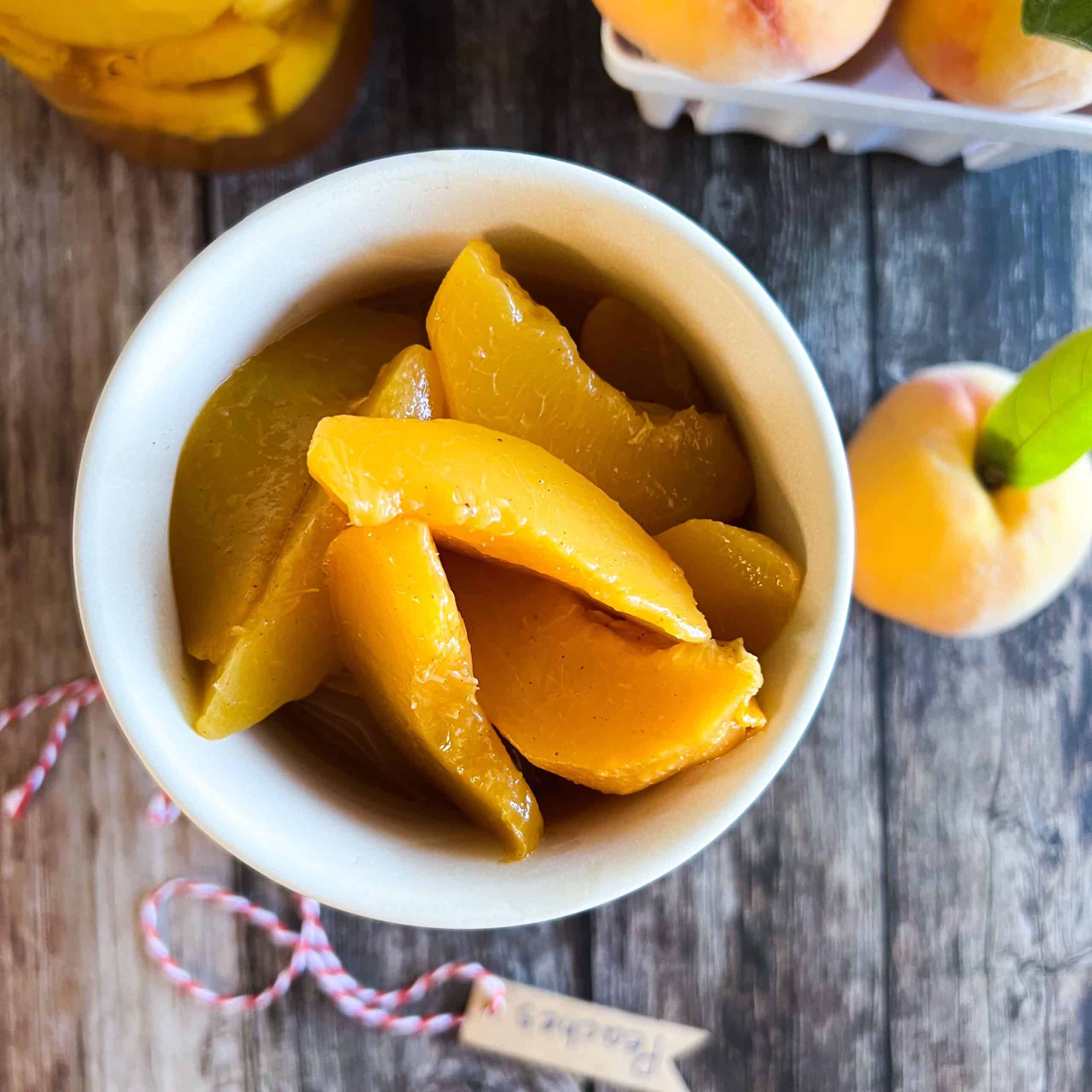 Spiced canned peaches with brown sugar in a cream bowl.