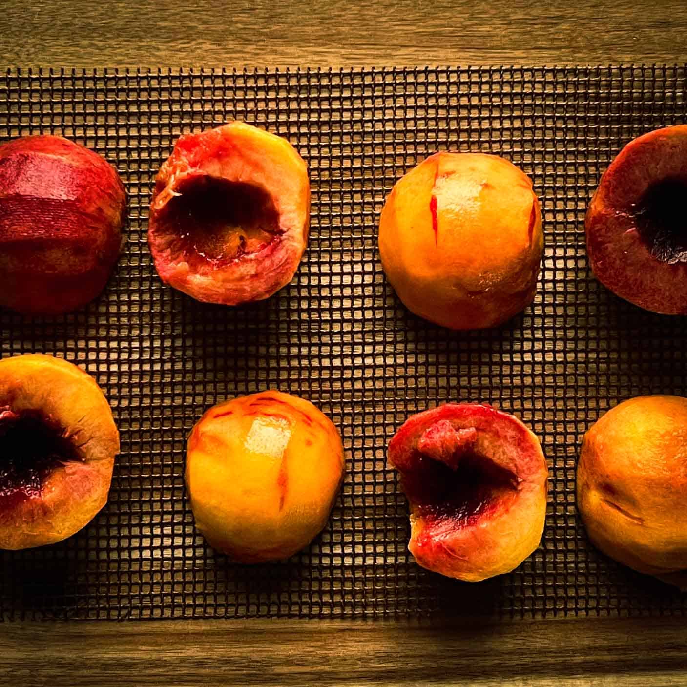 Peaches peeled, halved and placed on a grill mat.