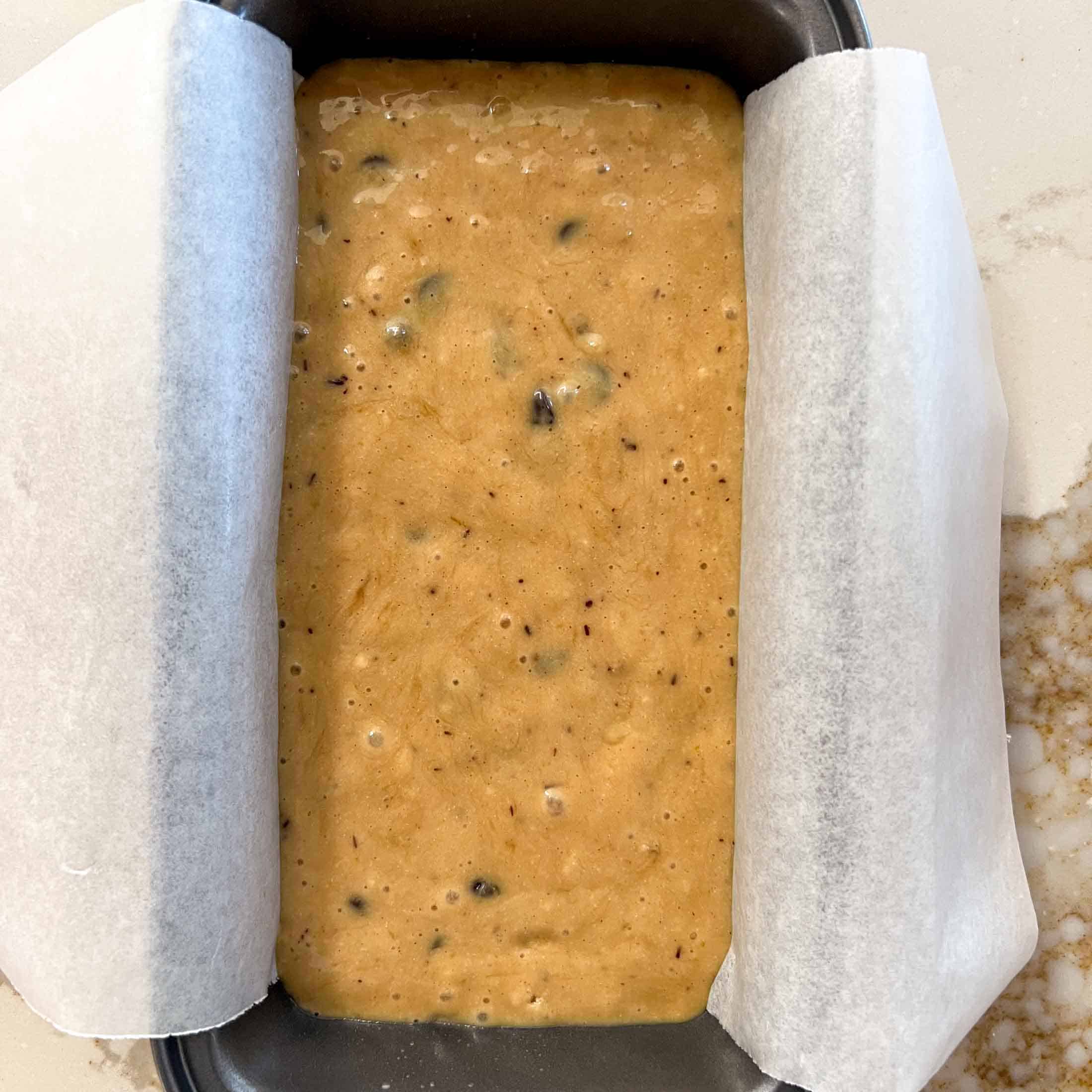 Raw banana bread batter with no butter in a small loaf pan lined with parchment paper.