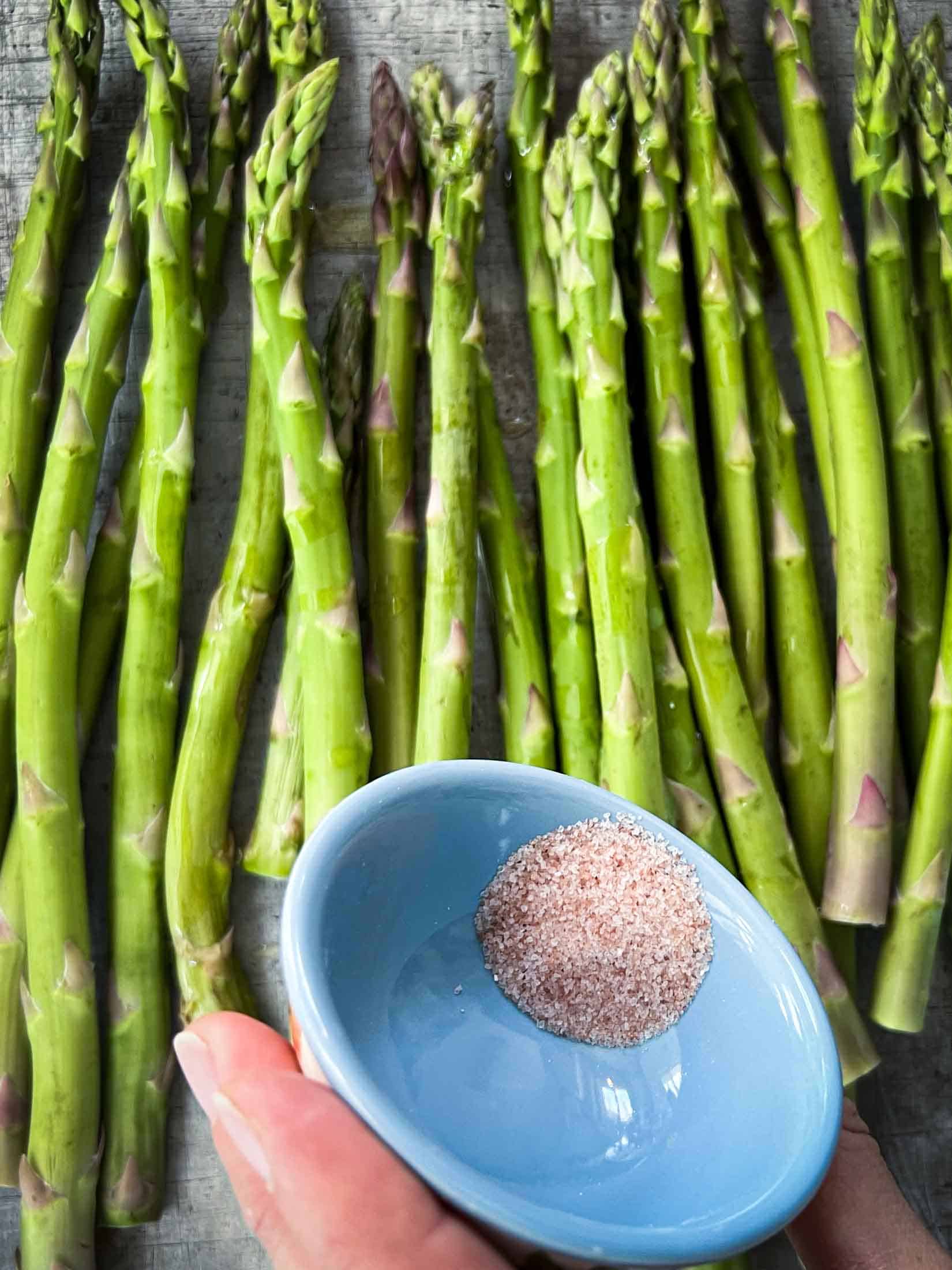 Salt being sprinkled onto asparagus spears before getting smoked.