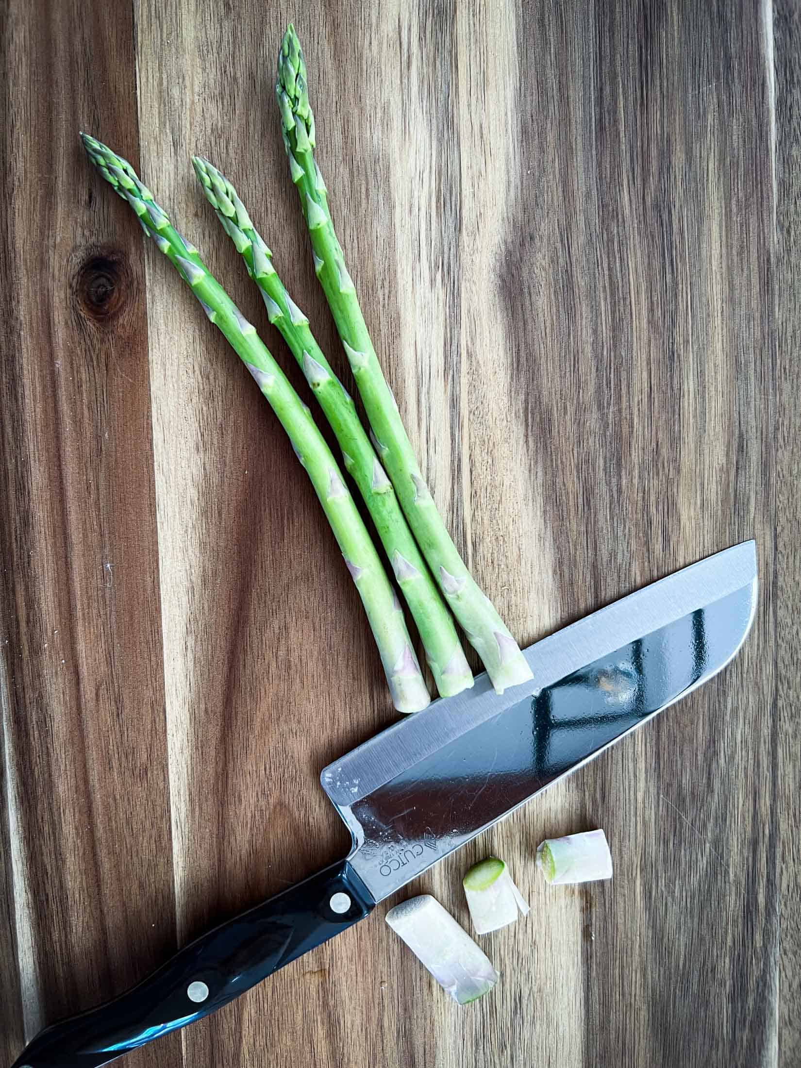 White ends being cut off of asparagus spears.