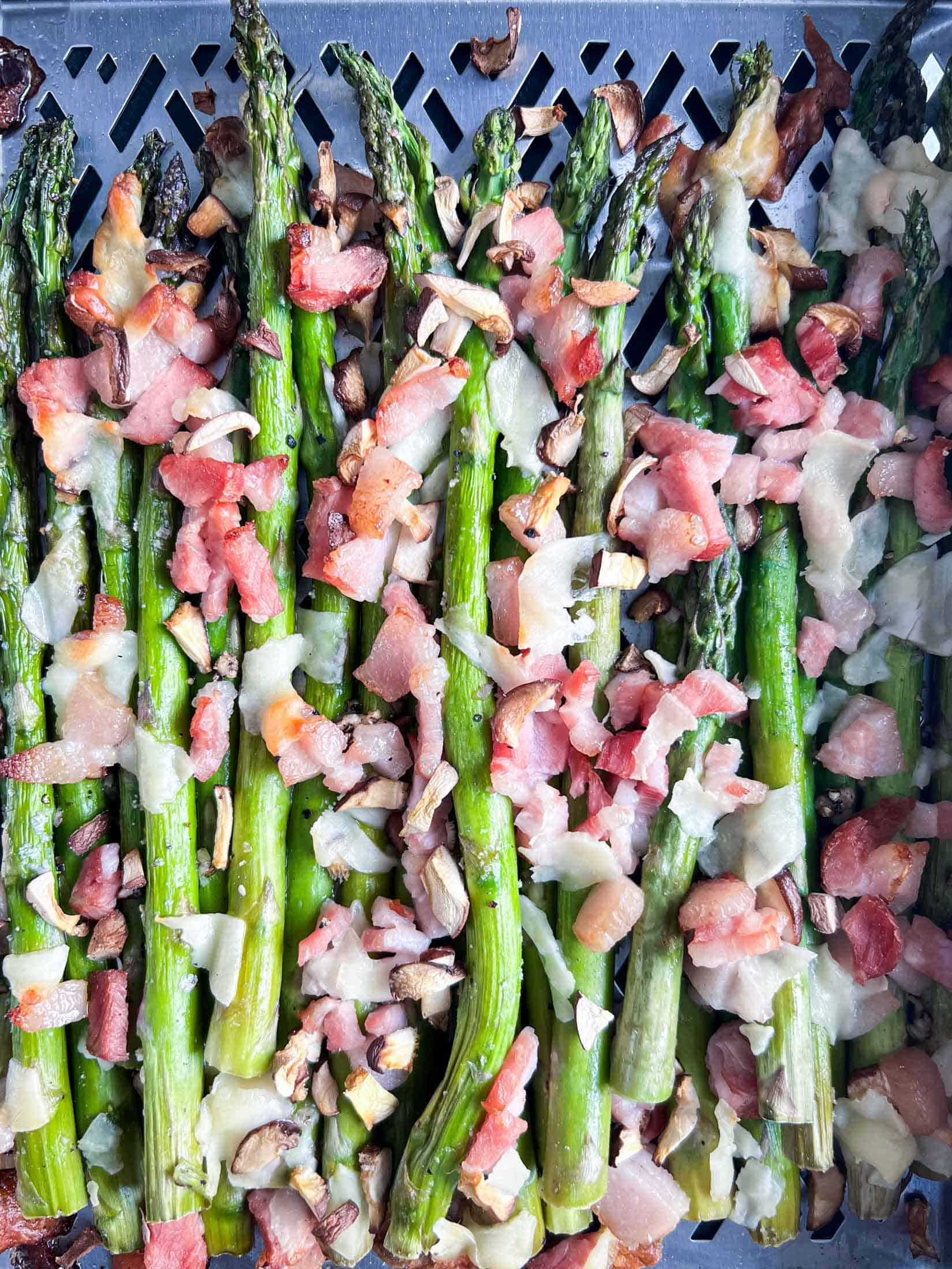 Loaded asparagus spears after being smoked on a Traeger pellet grill. Sprinkled with bacon, parmesan, and mushrooms.