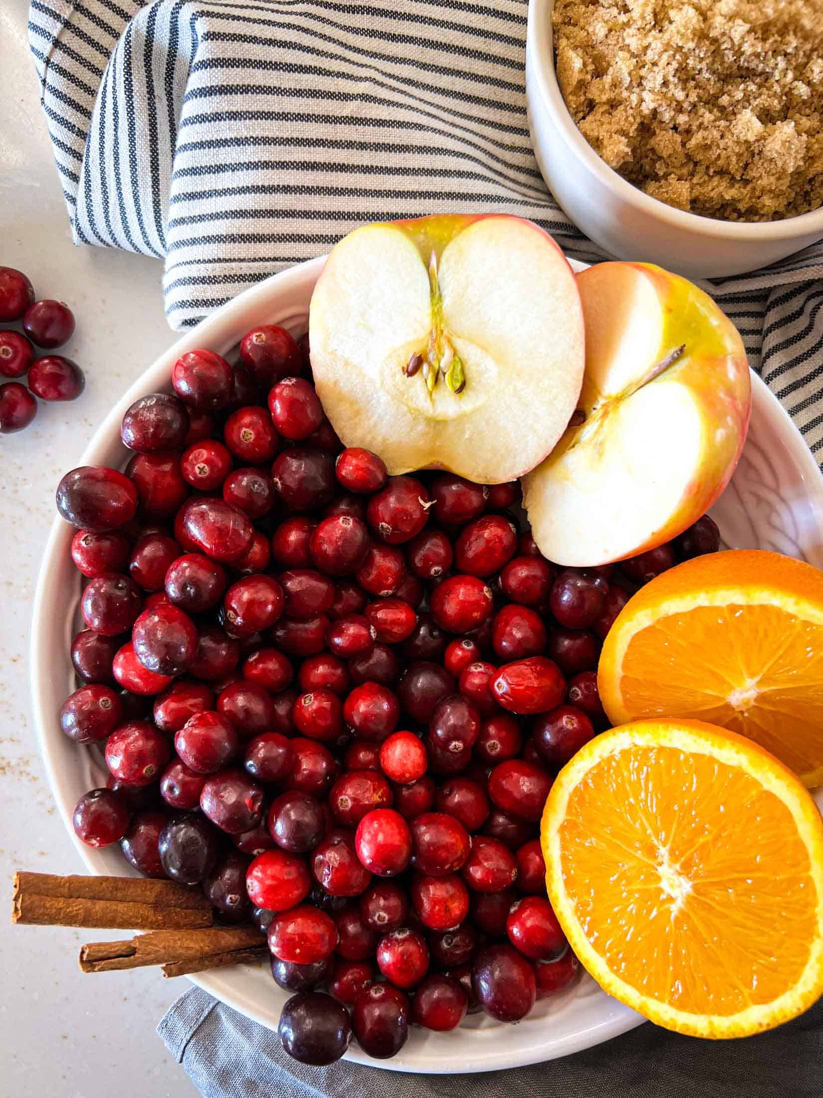 Key ingredients for smoked cranberry sauce including oranges, cranberries, cinnamon, apples, and brown sugar