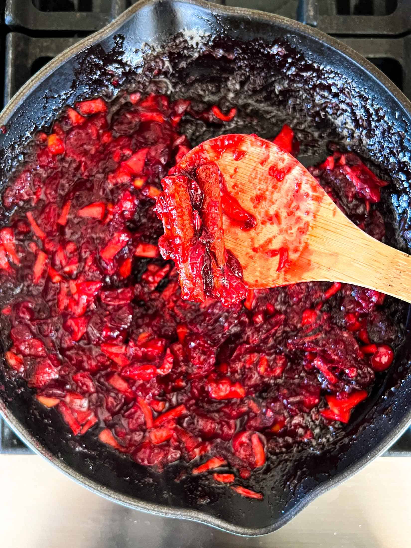 Smoked cranberry sauce after being cooked down, closeup on a wooden spoon.