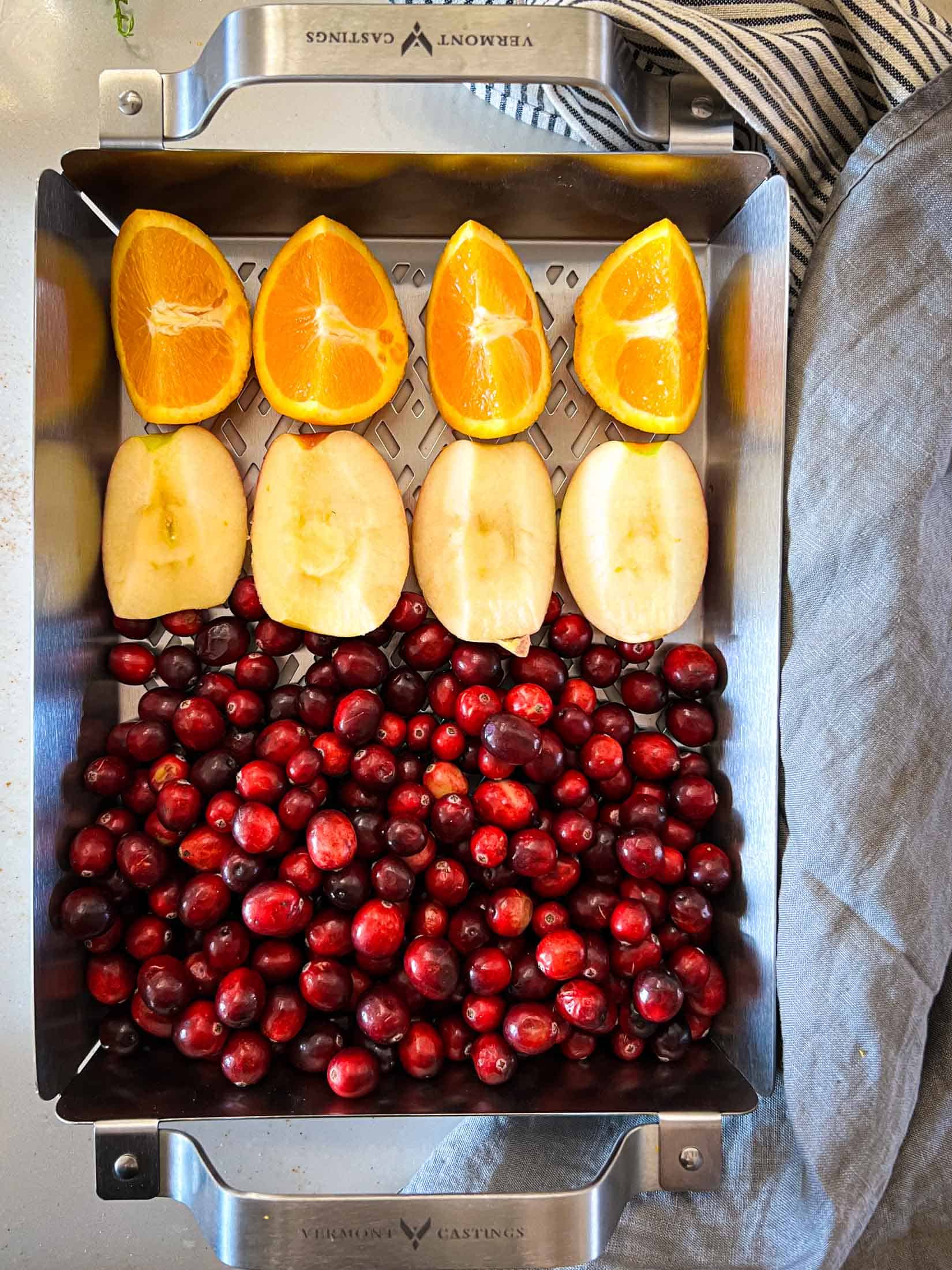 Oranges, cranberries and apples in a grill pan.