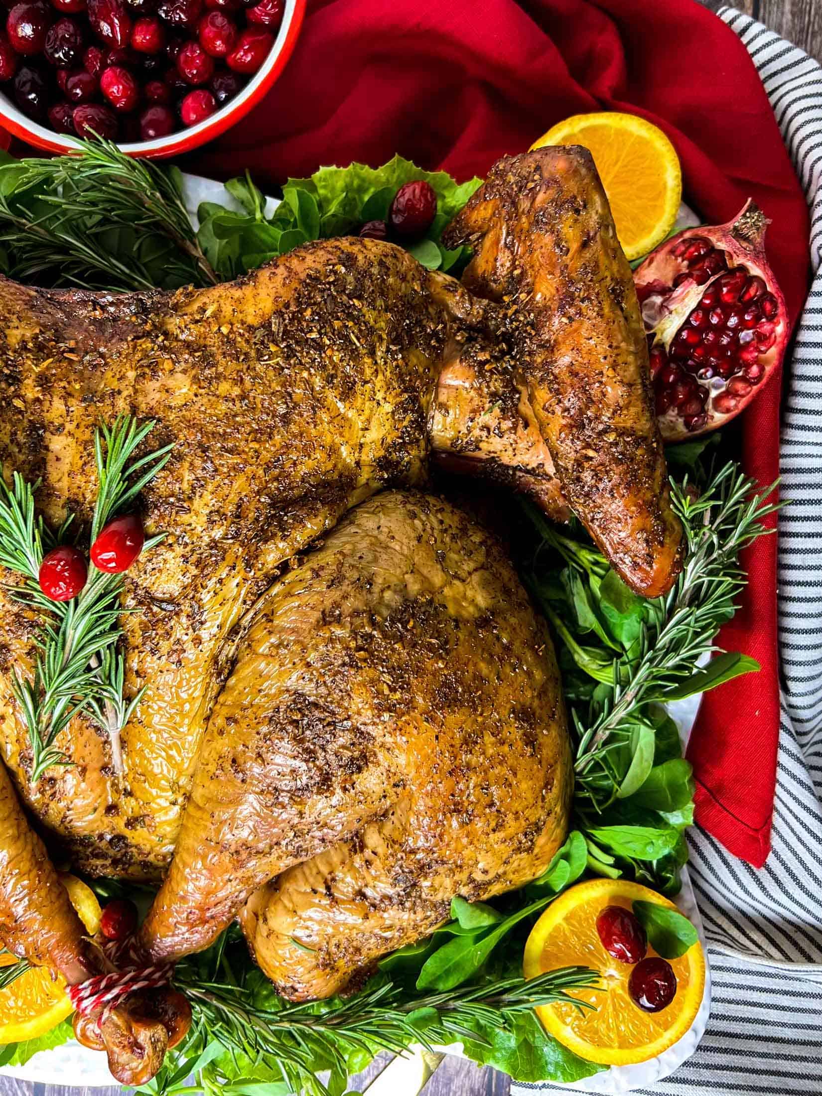 Smoked spatchcocked turkey with rosemary, cranberries, orange peels, and greens.