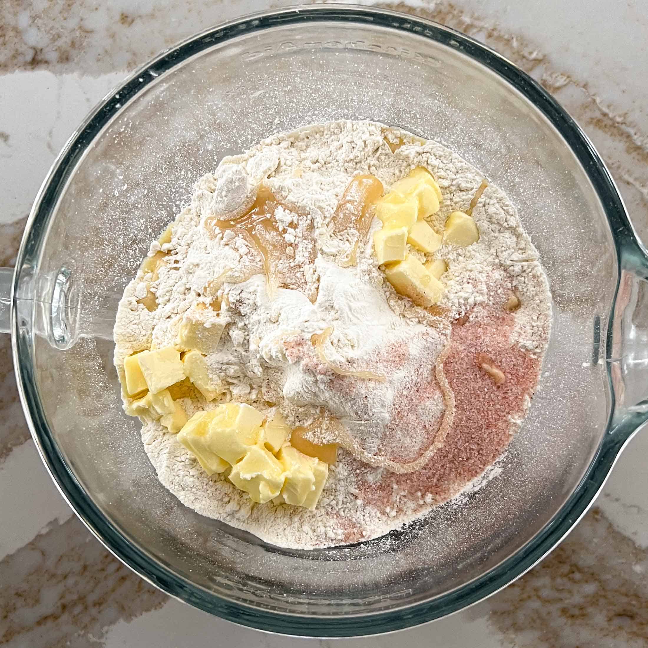 Butter, salt, honey, flour in a glass mixing bowl.