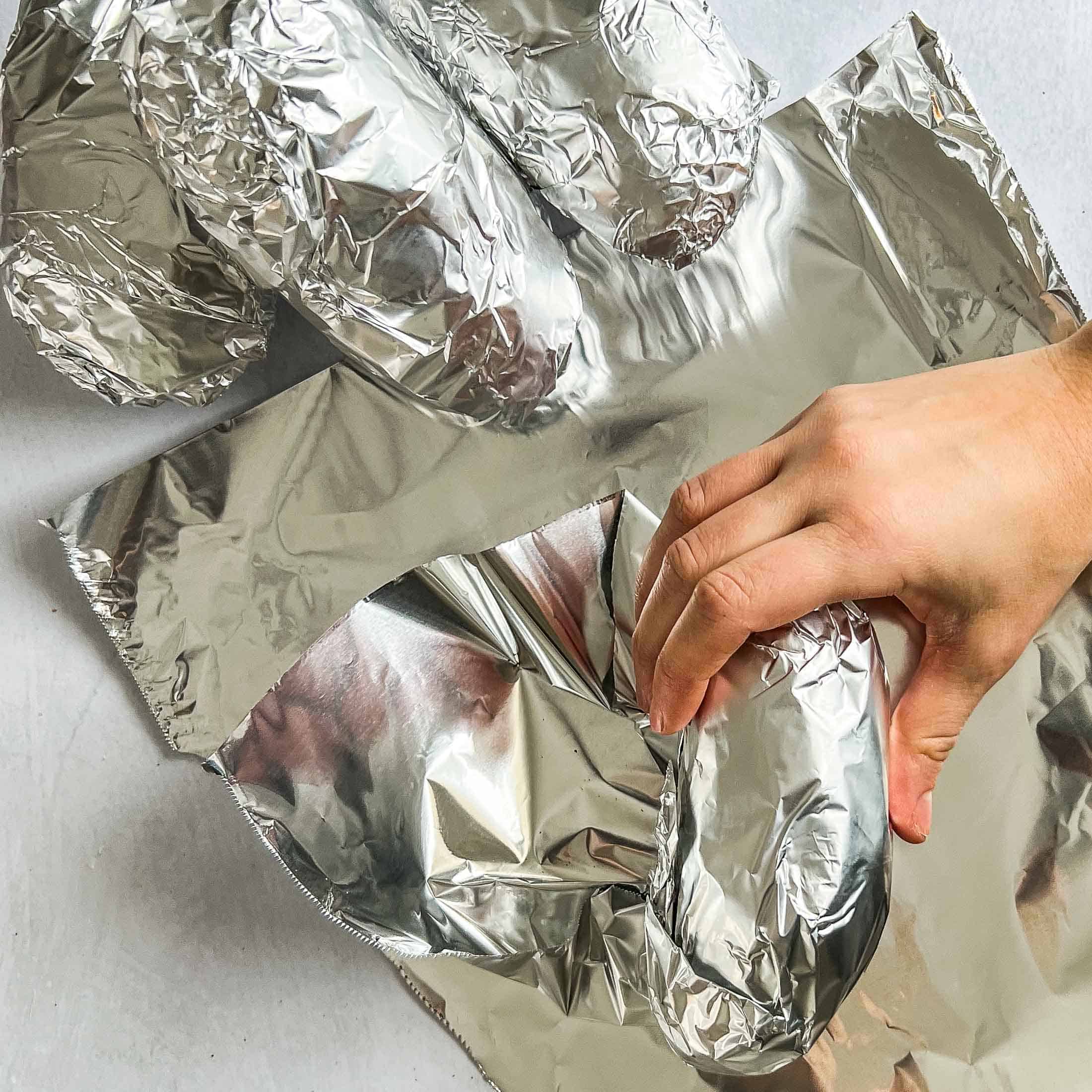 Wrapping a potato in aluminum foil before smoking.