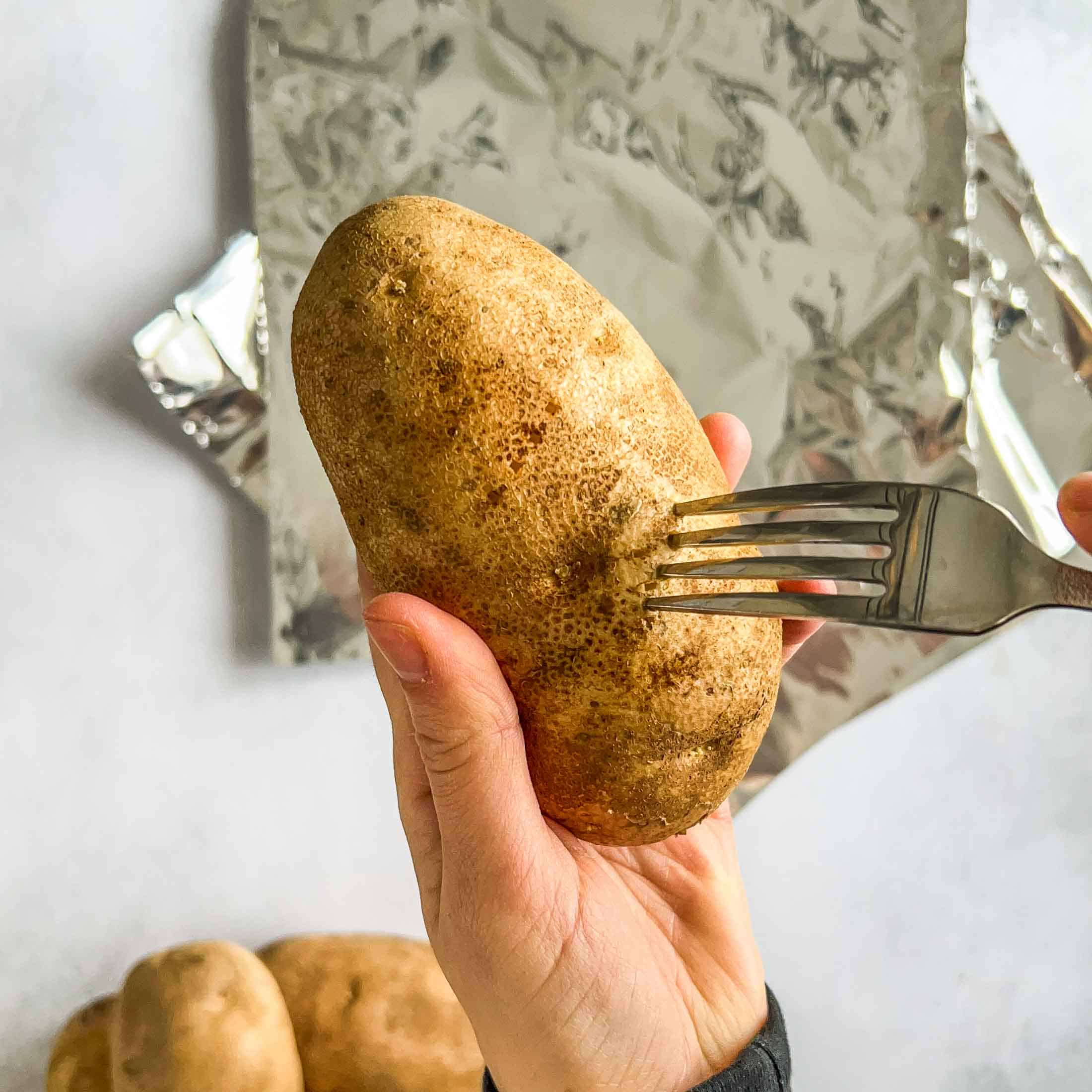 Poking holes in a potato before wrapping in foil and smoking.