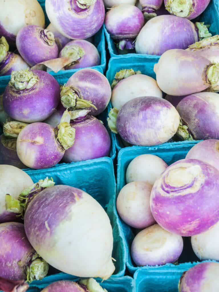 Purple and white turnips in small blue crates.