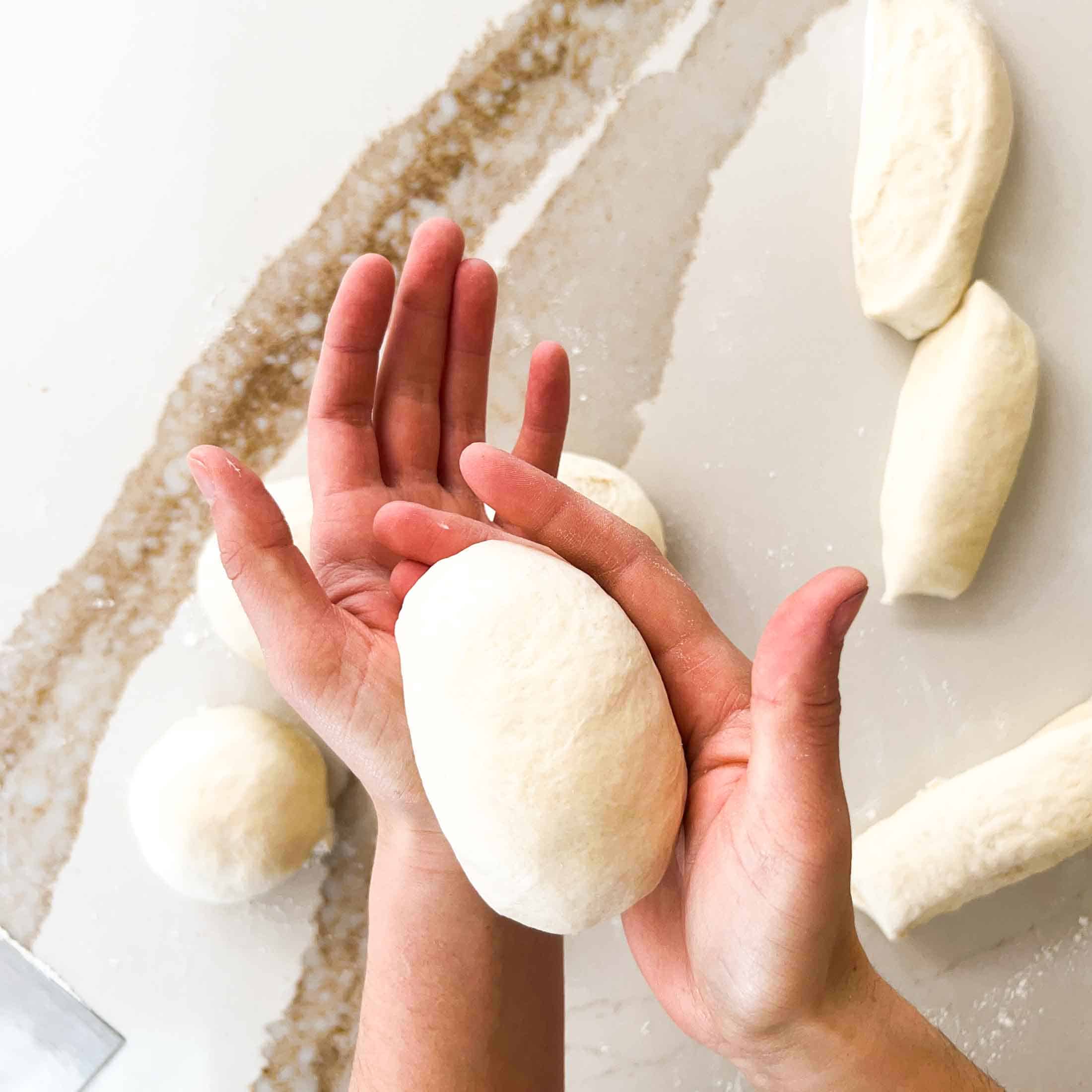 Tightening a ball of dough into a bun shape.