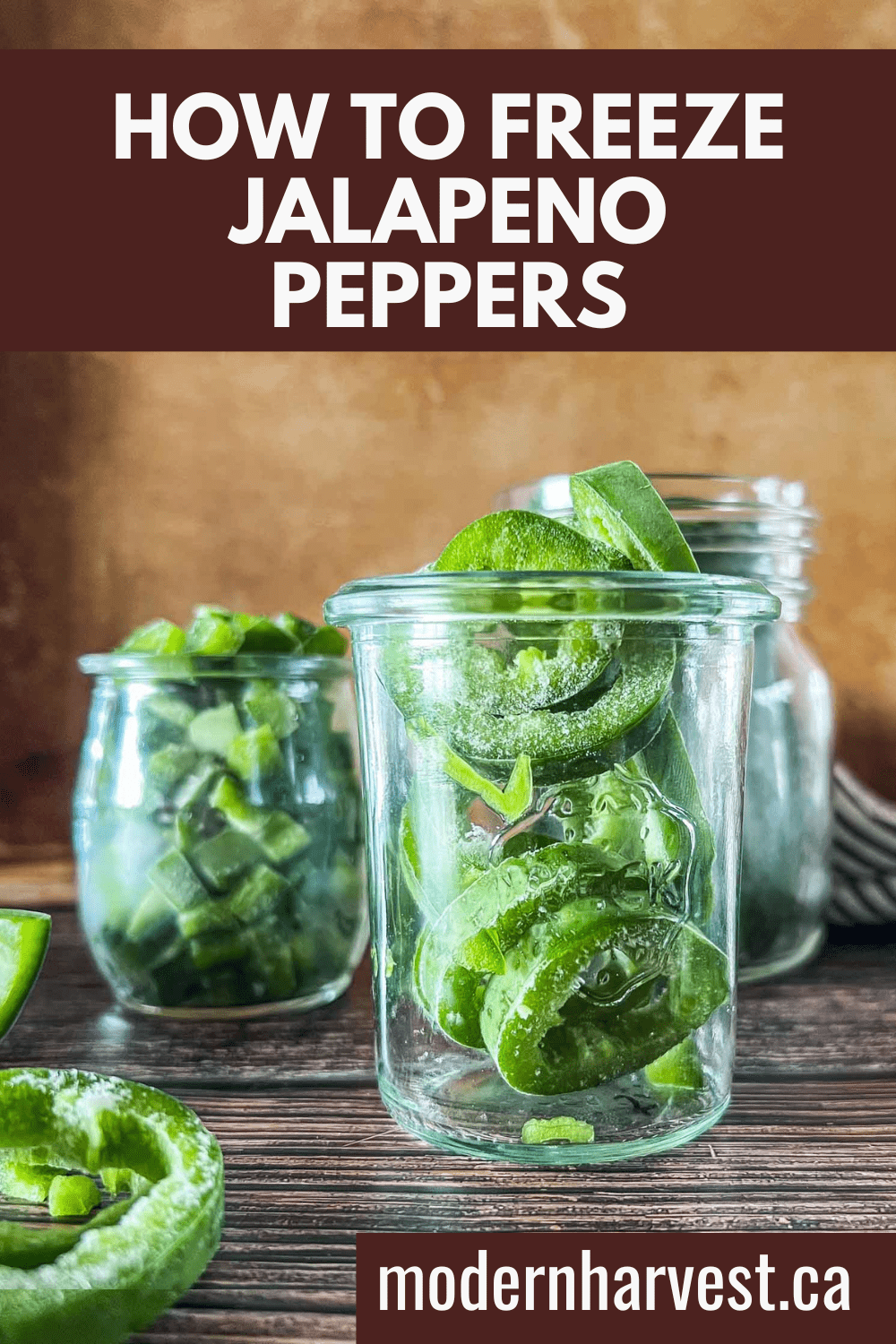 Frozen jalapenos in a glass jars with more frozen pieces scattered on a wooden surface.