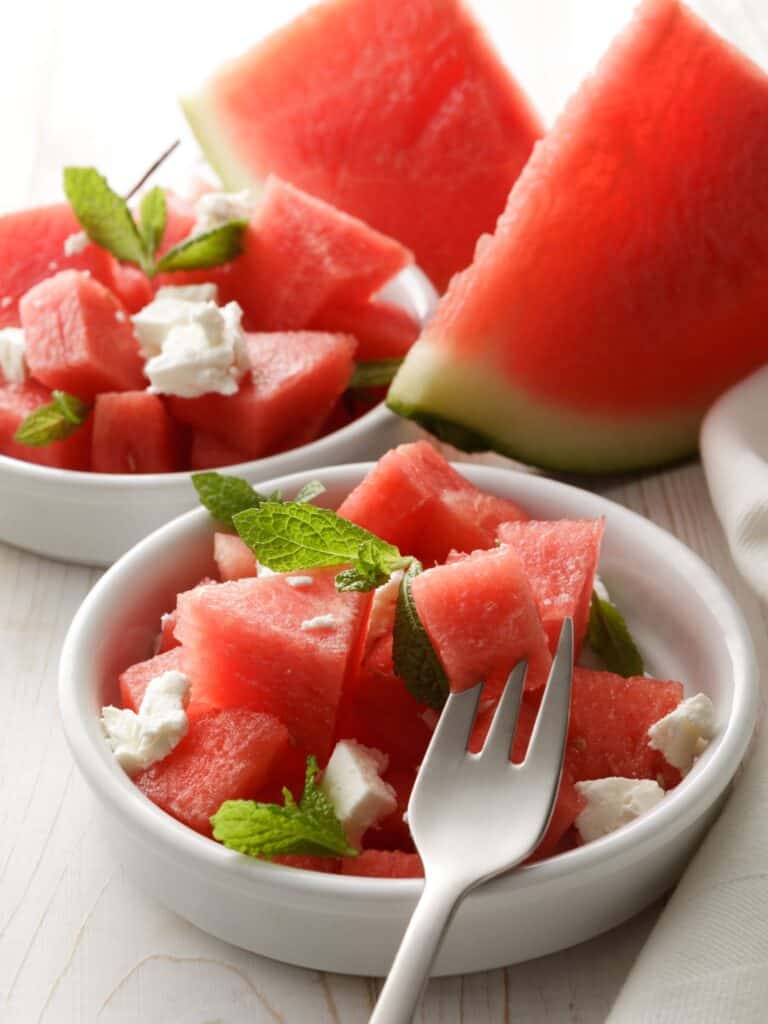 Watermelon salad including mint and feta chopped on a white plate.