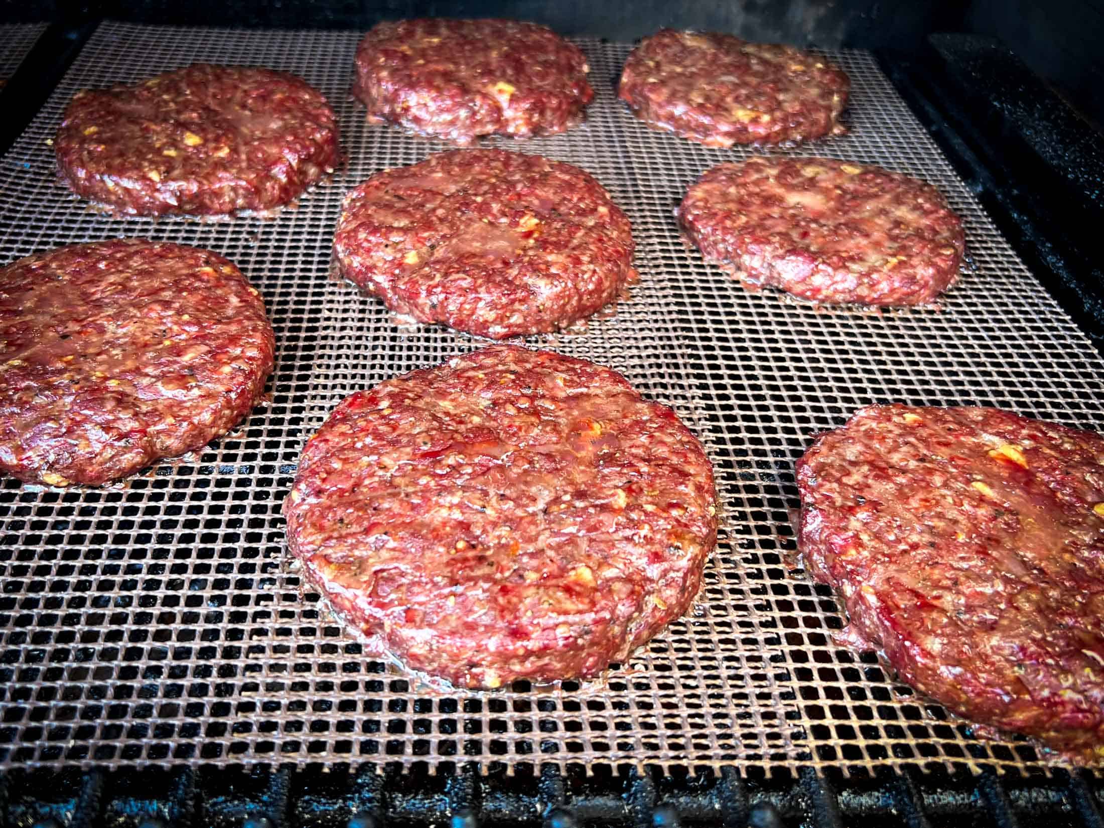 Fully cooked venison burgers on a grill.
