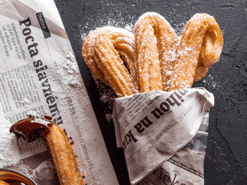 Freshly powdered churros wrapped in newspaper.