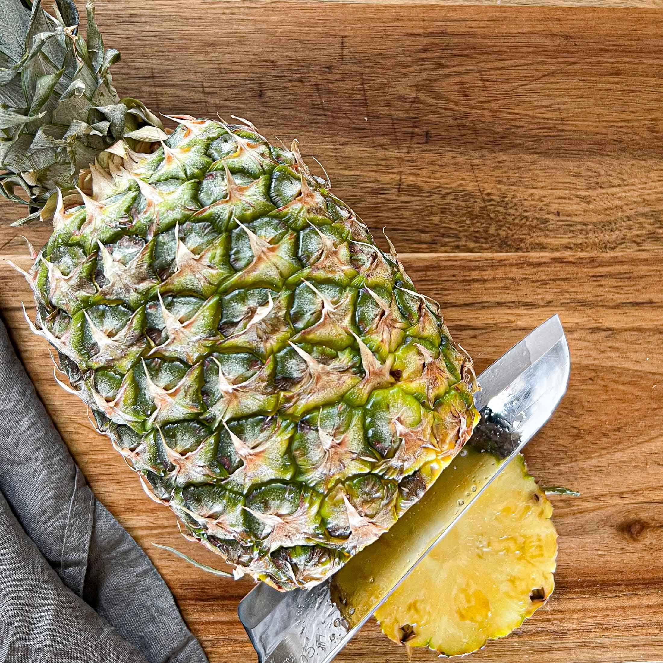 Slicing off the bottom of a pineapple.