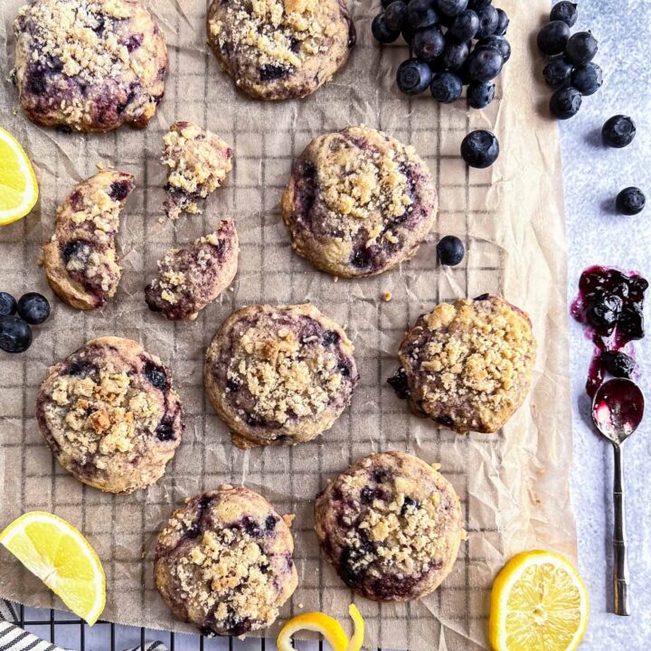 Lemon blueberry cookies on a piece of brown parchment with blueberries and sliced lemons.