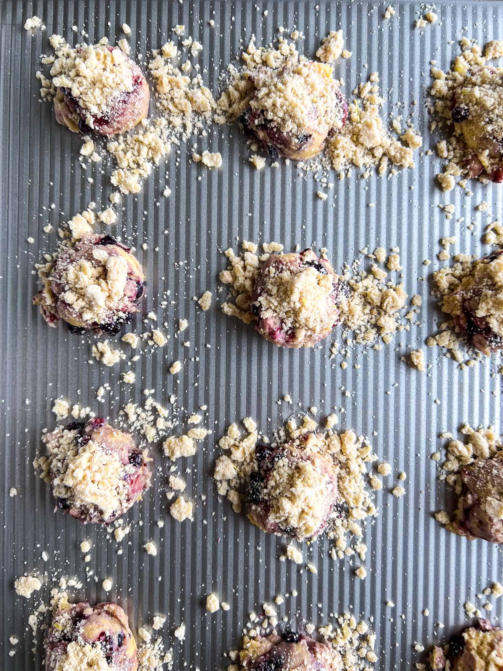 Uncooked lemon blueberry cookies dropped on a large baking sheet with crumble topping.