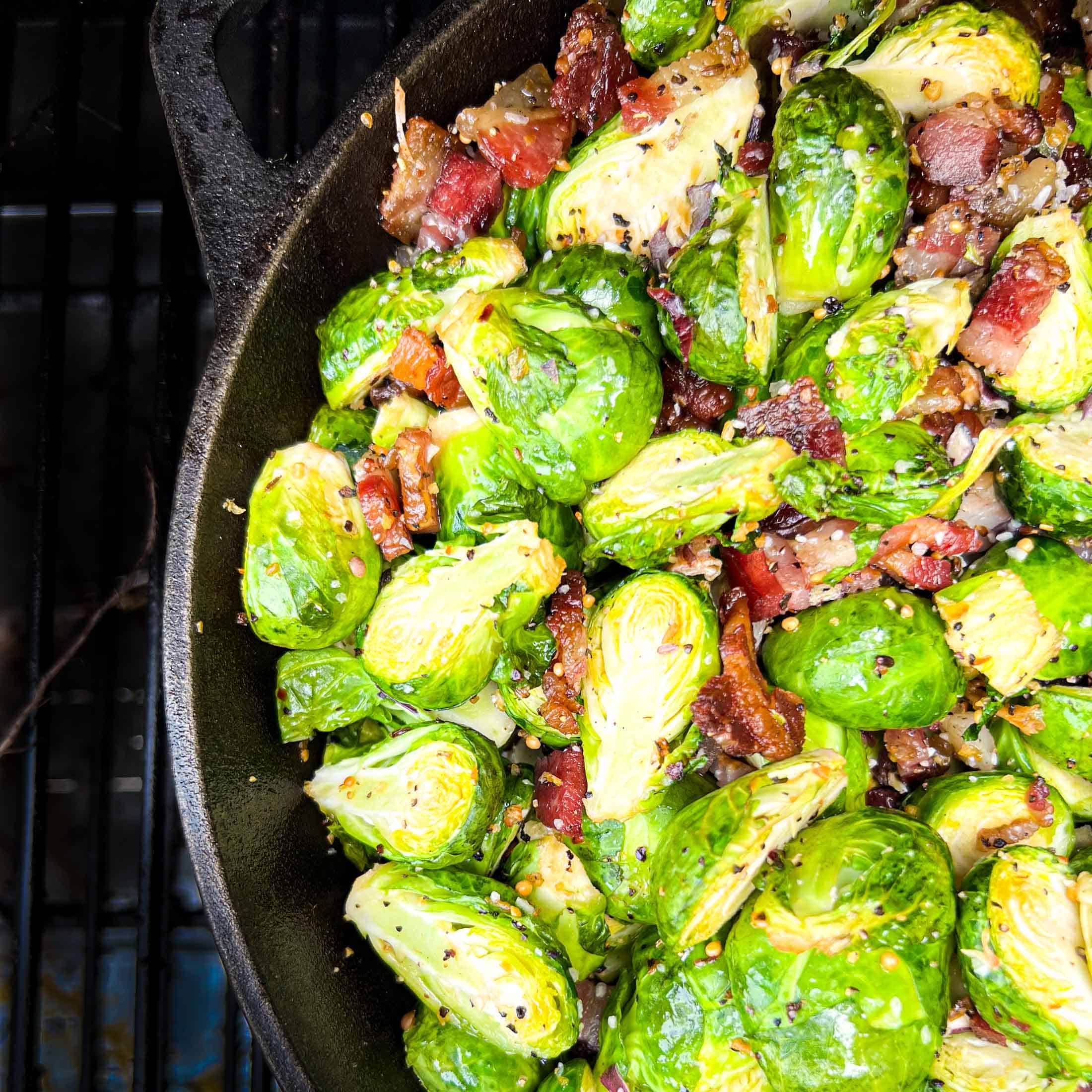 Crispy brussels sprouts in a cast iron skillet on the smoker.