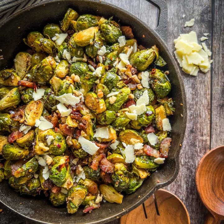 Crispy brussels sprouts in a cast iron skillet with balsamic glaze drizzled on top on the smoker.