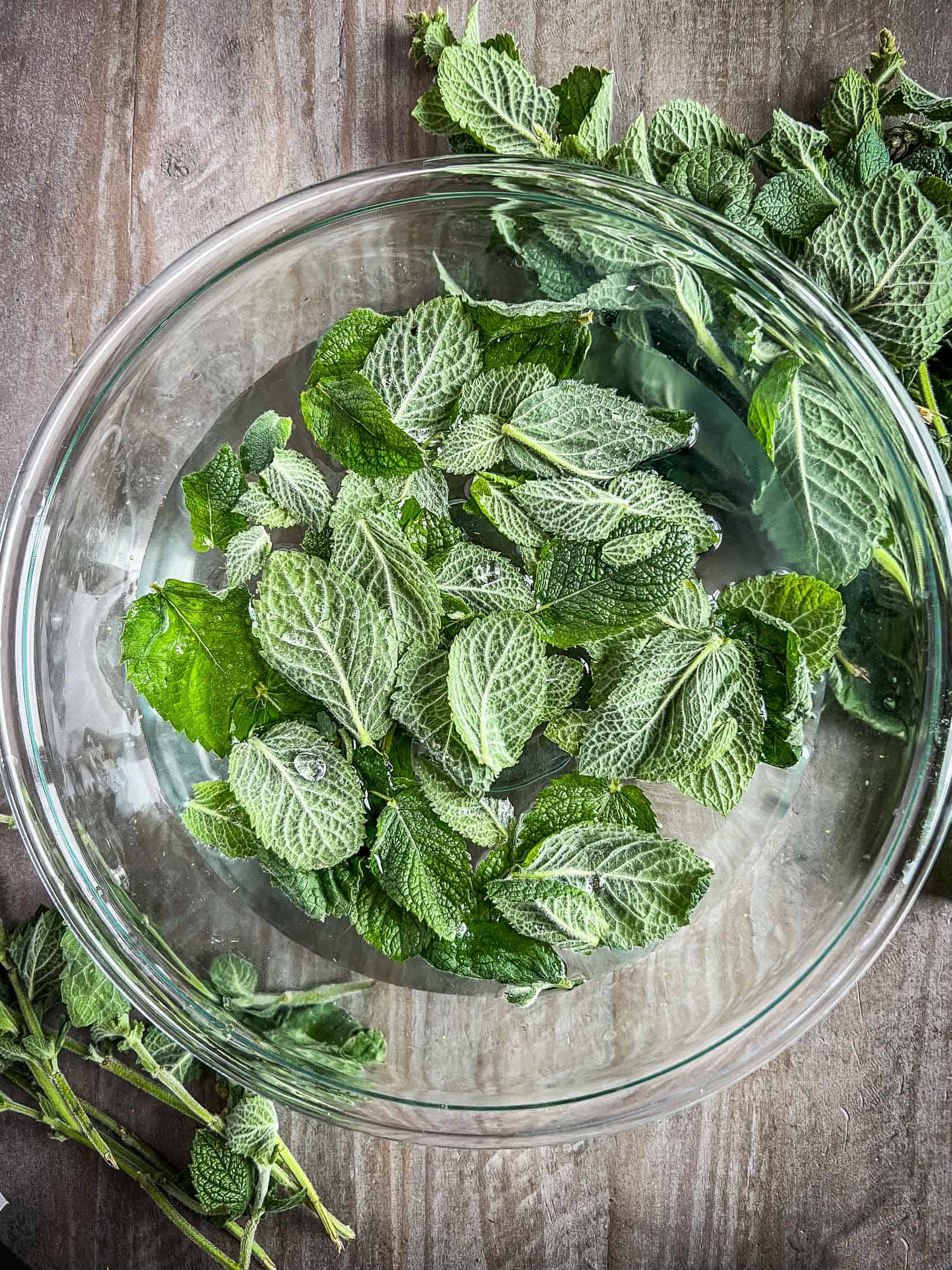 Mint leaves in a glass bowl of water.