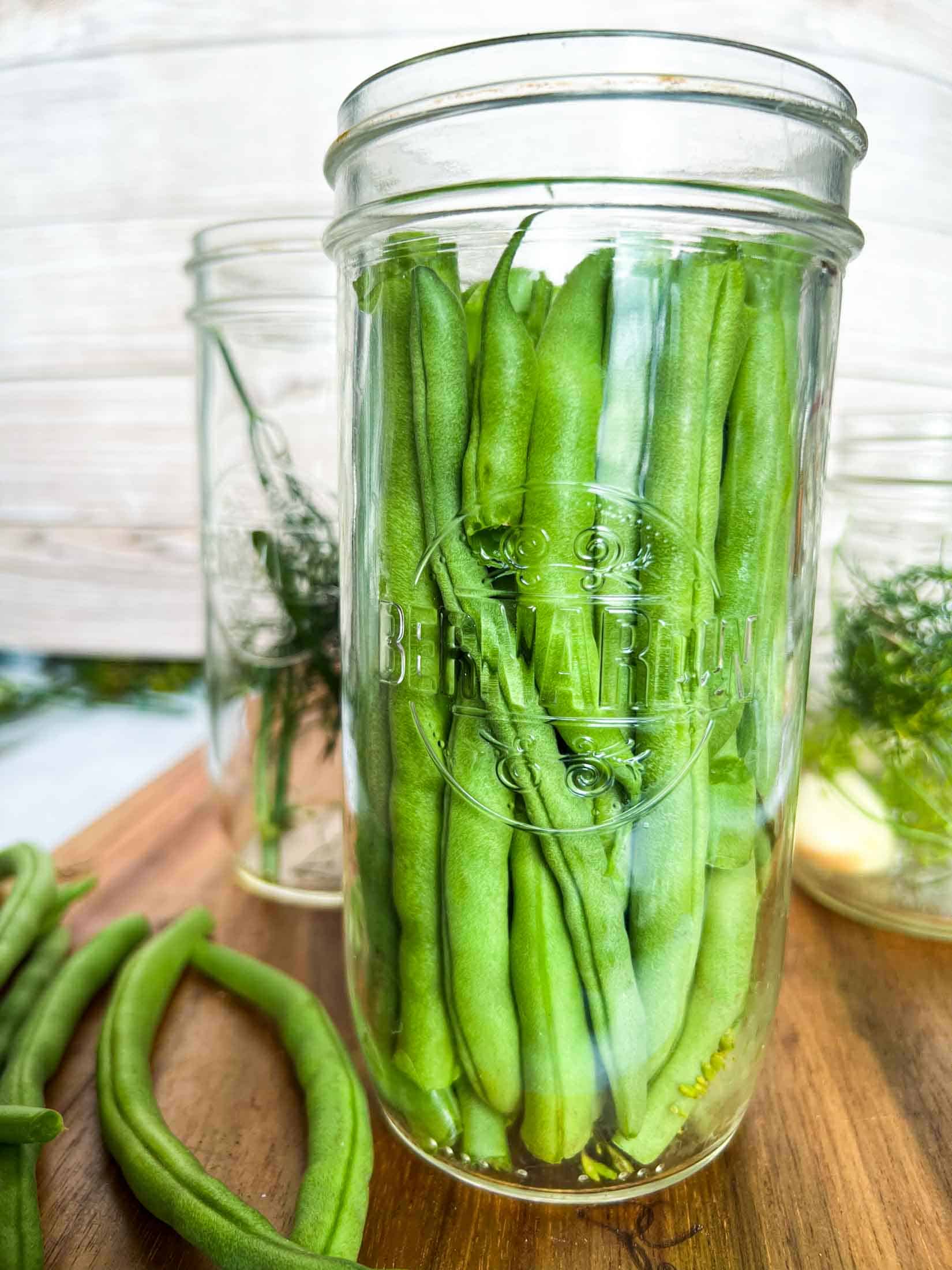 Green beans standing vertically in a pint and a half sized jar.