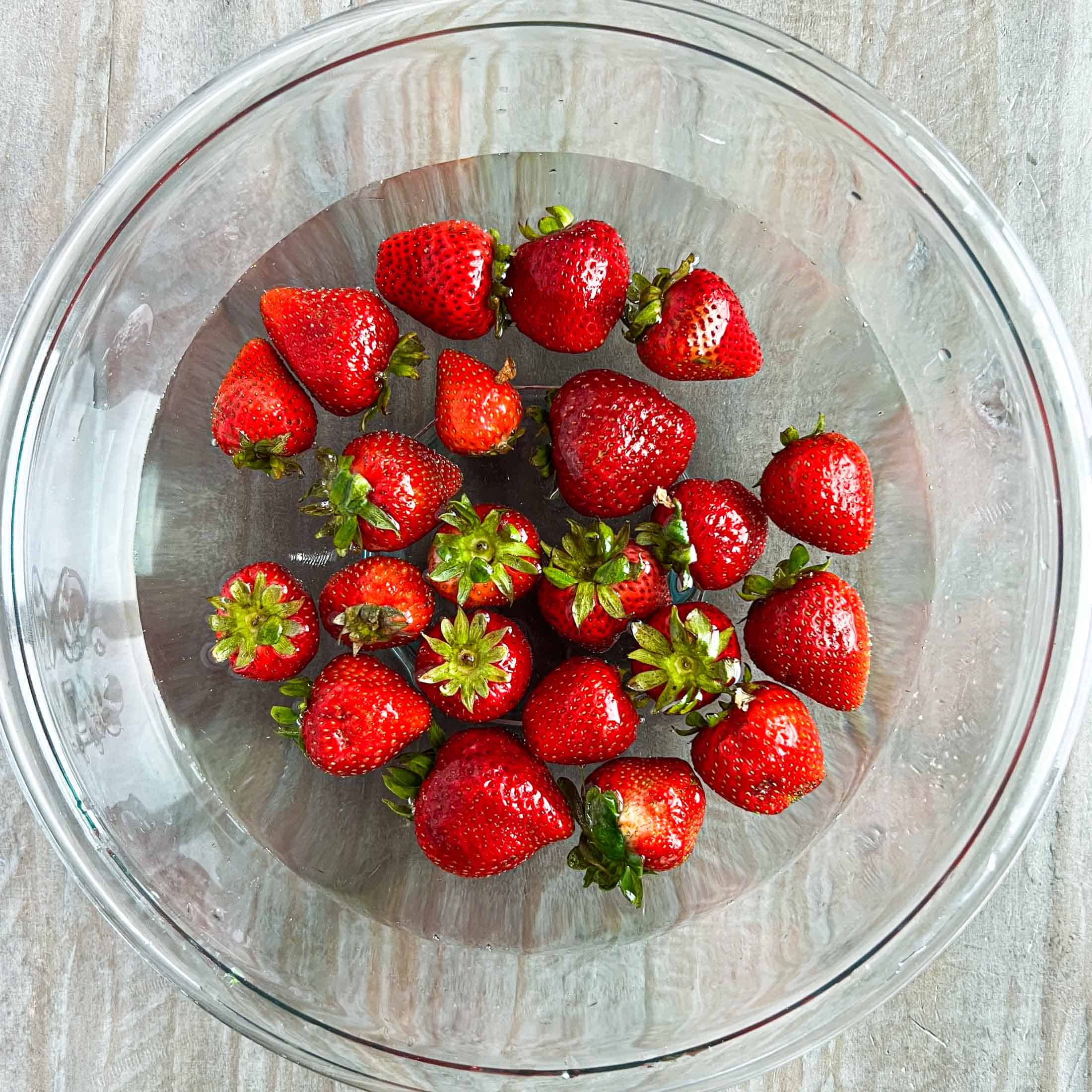 Strawberries in a glass bowl with water.