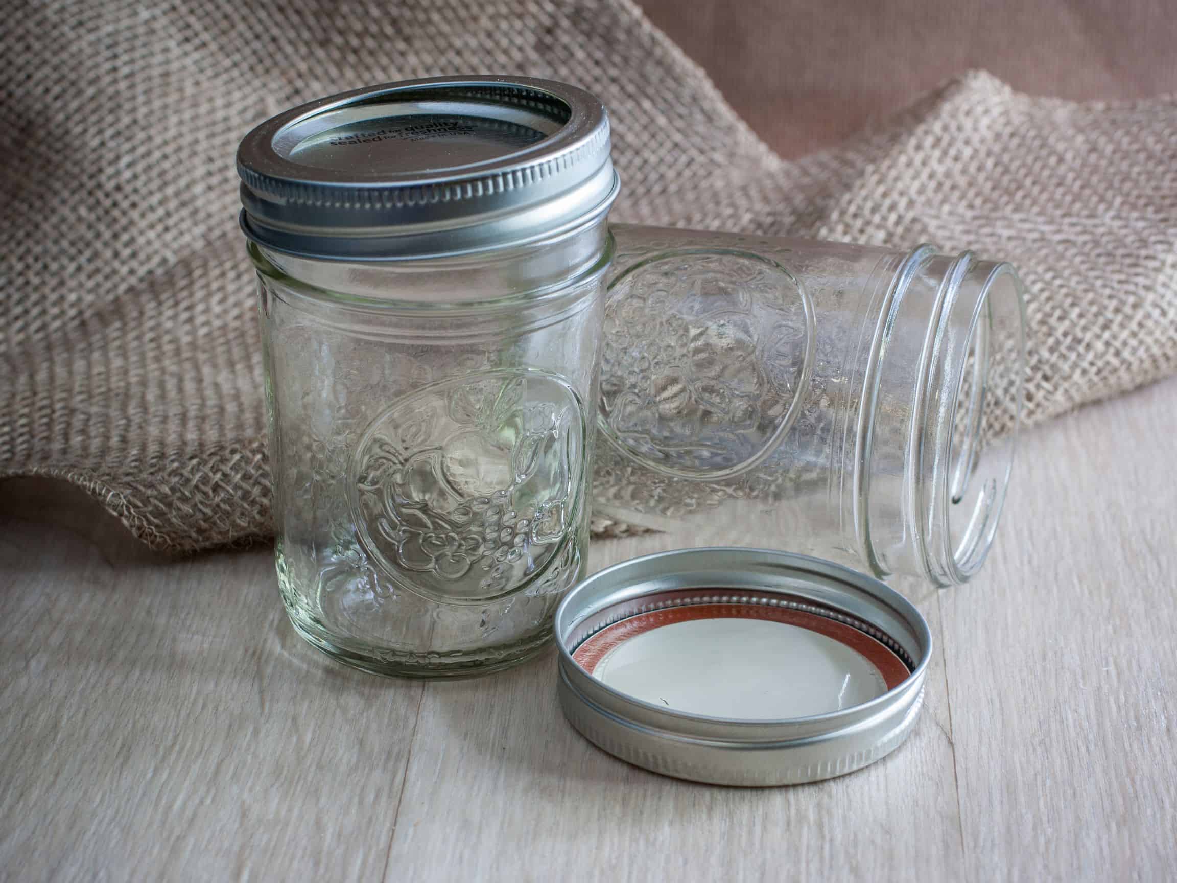 Two empty mason jars on a wooden surface.