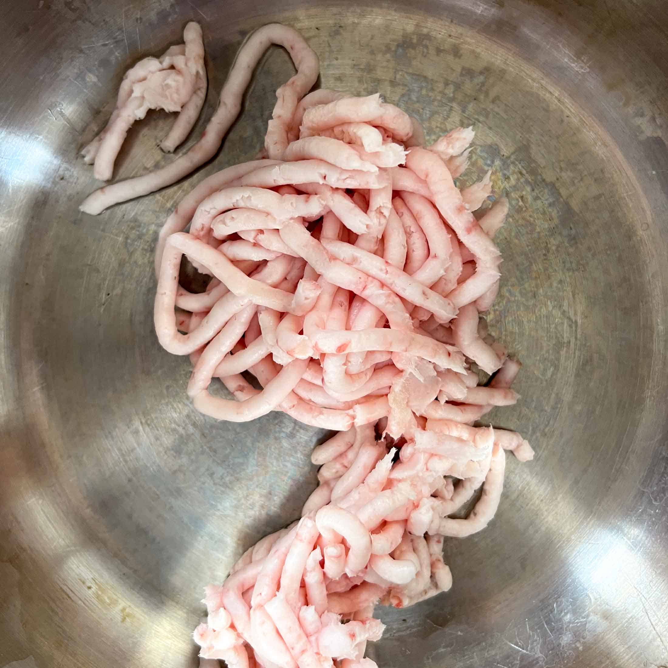 Ground strings of lard sitting at the bottom of a heavy stock pot.
