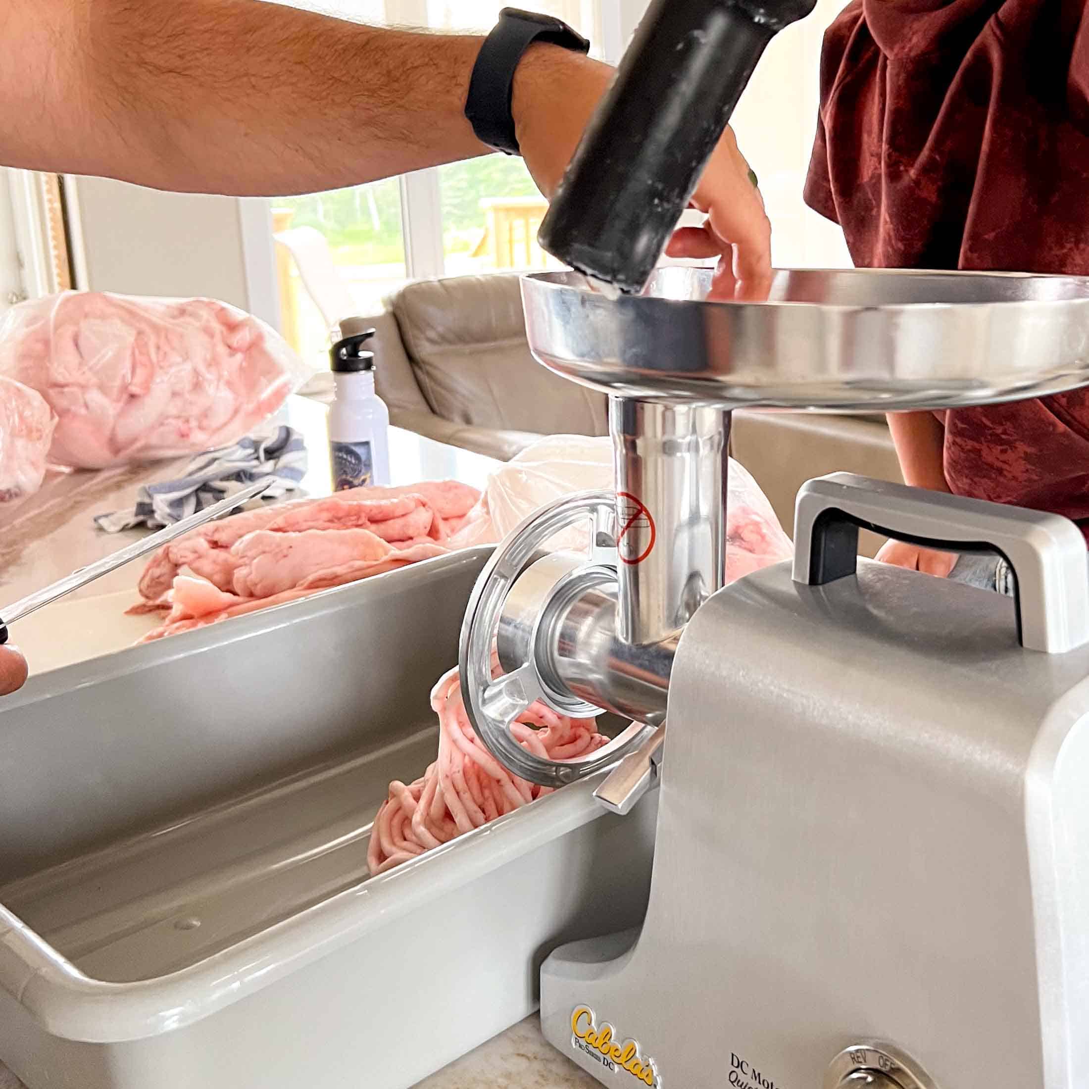 Lard being pushed into a meat grinder with a black plunger.