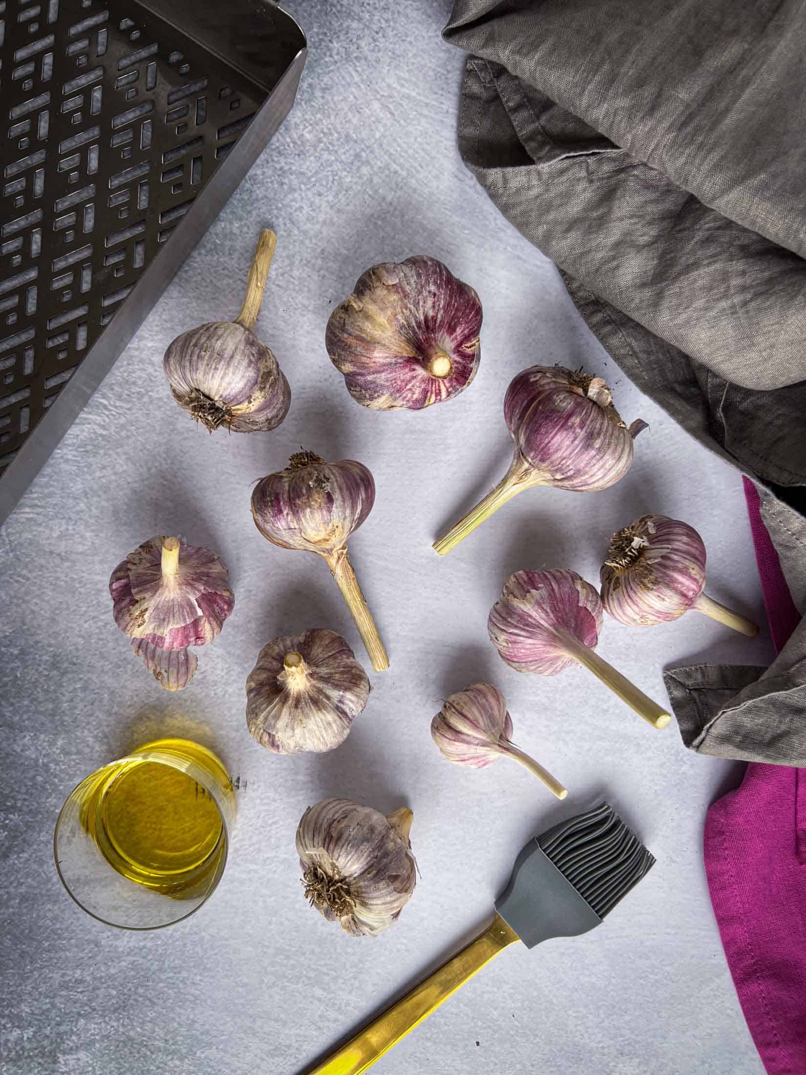 Key ingredients for Traeger garlic recipe 9 heads of garlic, olive oil, and a basting brush.